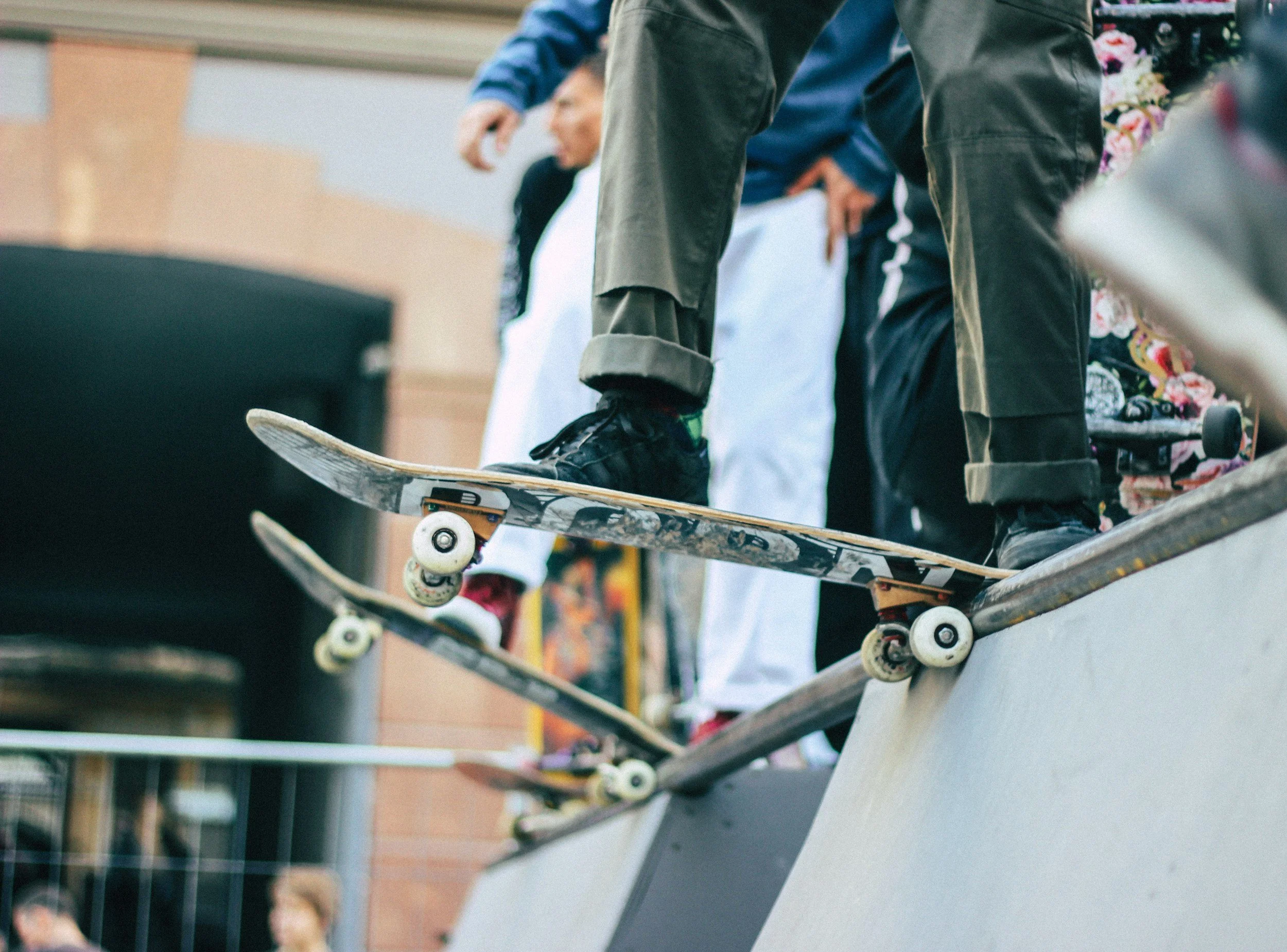 Skateboarders at a skatepark with their skateboards on a ledge, some standing and others preparing to ride.