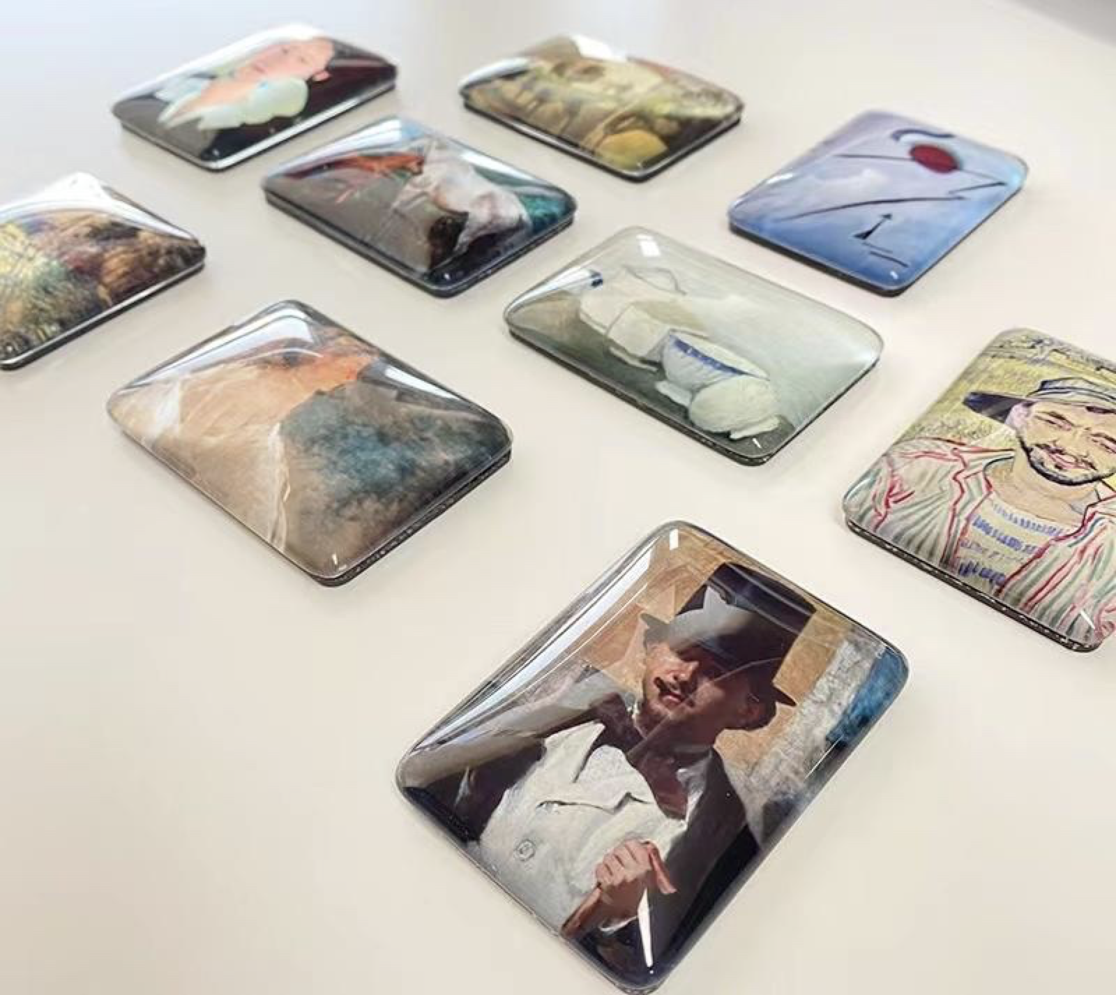 Collection of custom designed phone cases with various artwork, including portraits, abstract patterns, and nature scenes, spread on a white surface.