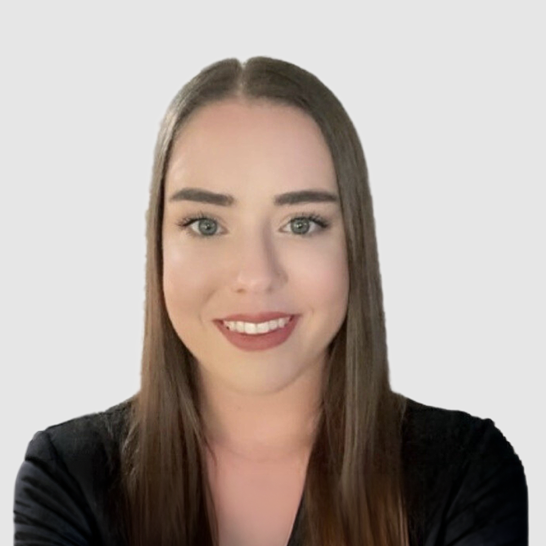 Close-up of a young woman with long brown hair, blue eyes, and a friendly smile, wearing a black top.