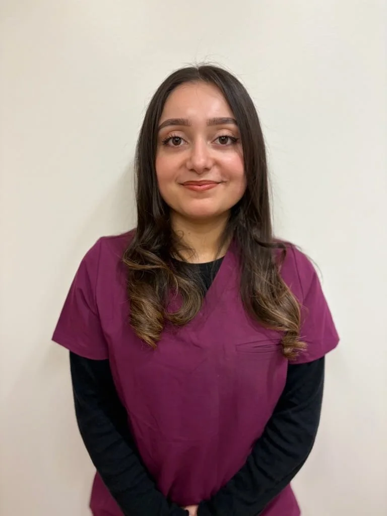 A woman in a pink medical uniform smiling at the camera.