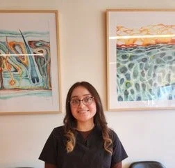 A woman in a pink medical uniform smiling at the camera.