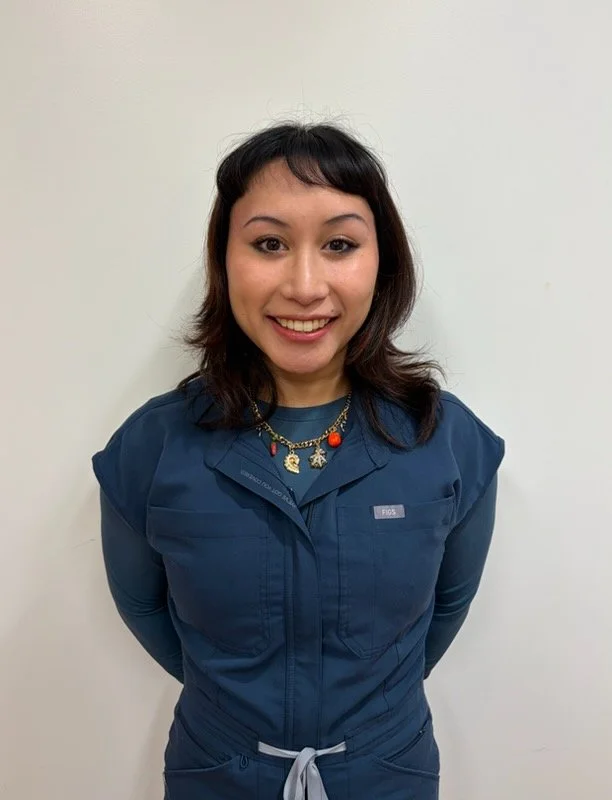 Young medical assistant smiling at the camera in an office setting.