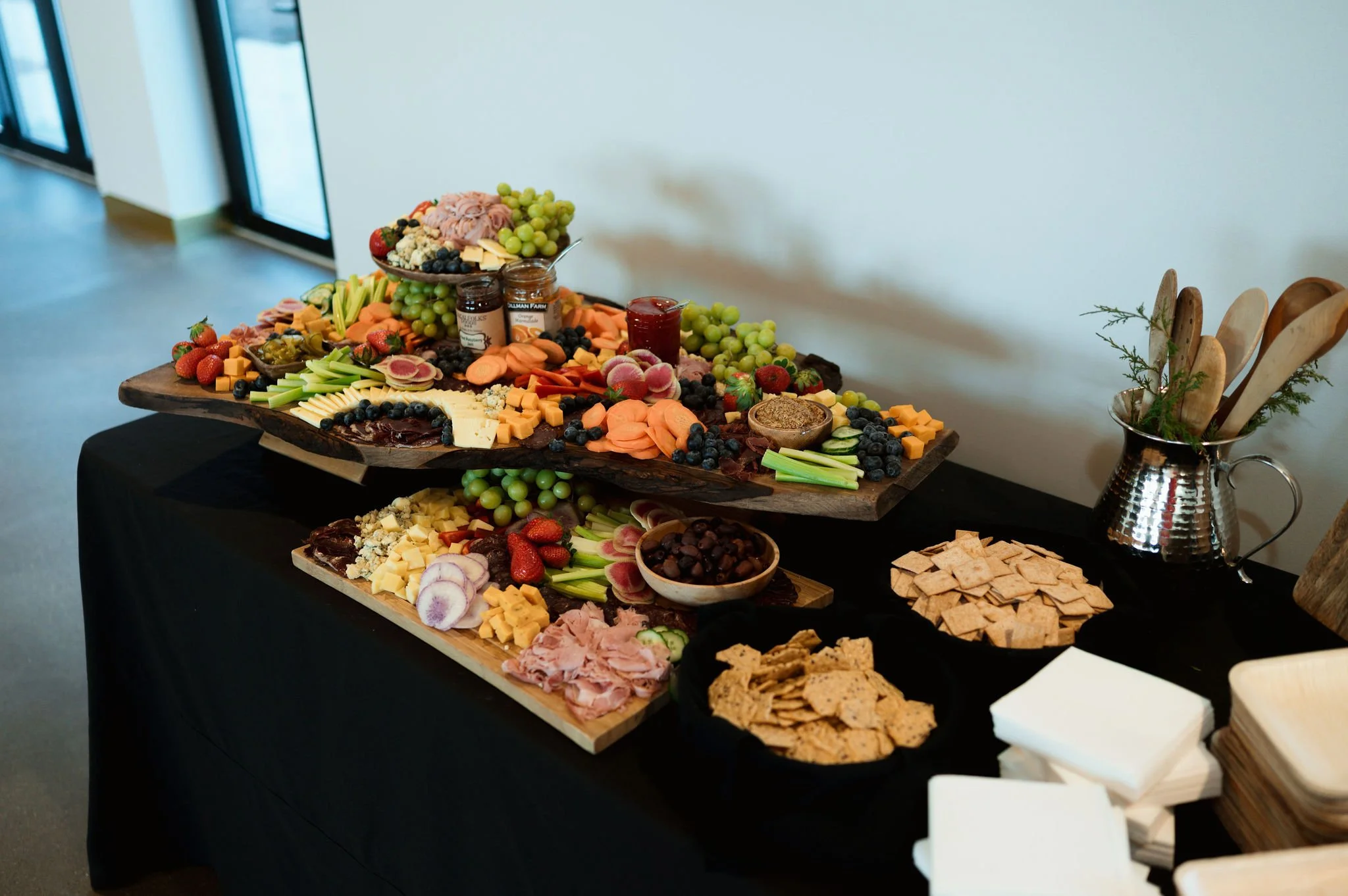 Assorted cheese, fruits, crackers, and meats on a wooden serving board for a charcuterie display.