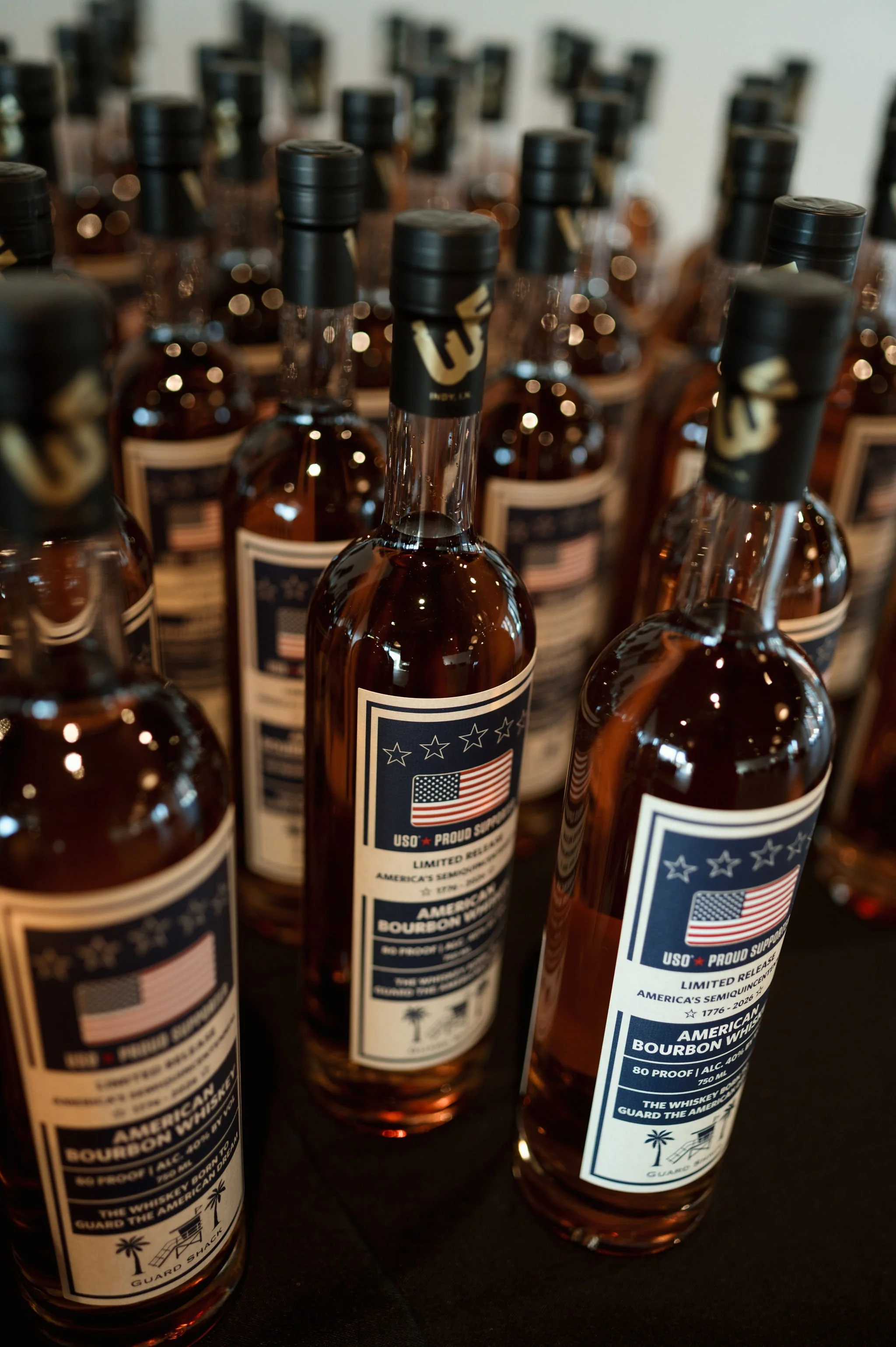 Several bottles of bourbon whiskey with American flag-themed labels on a dark surface.