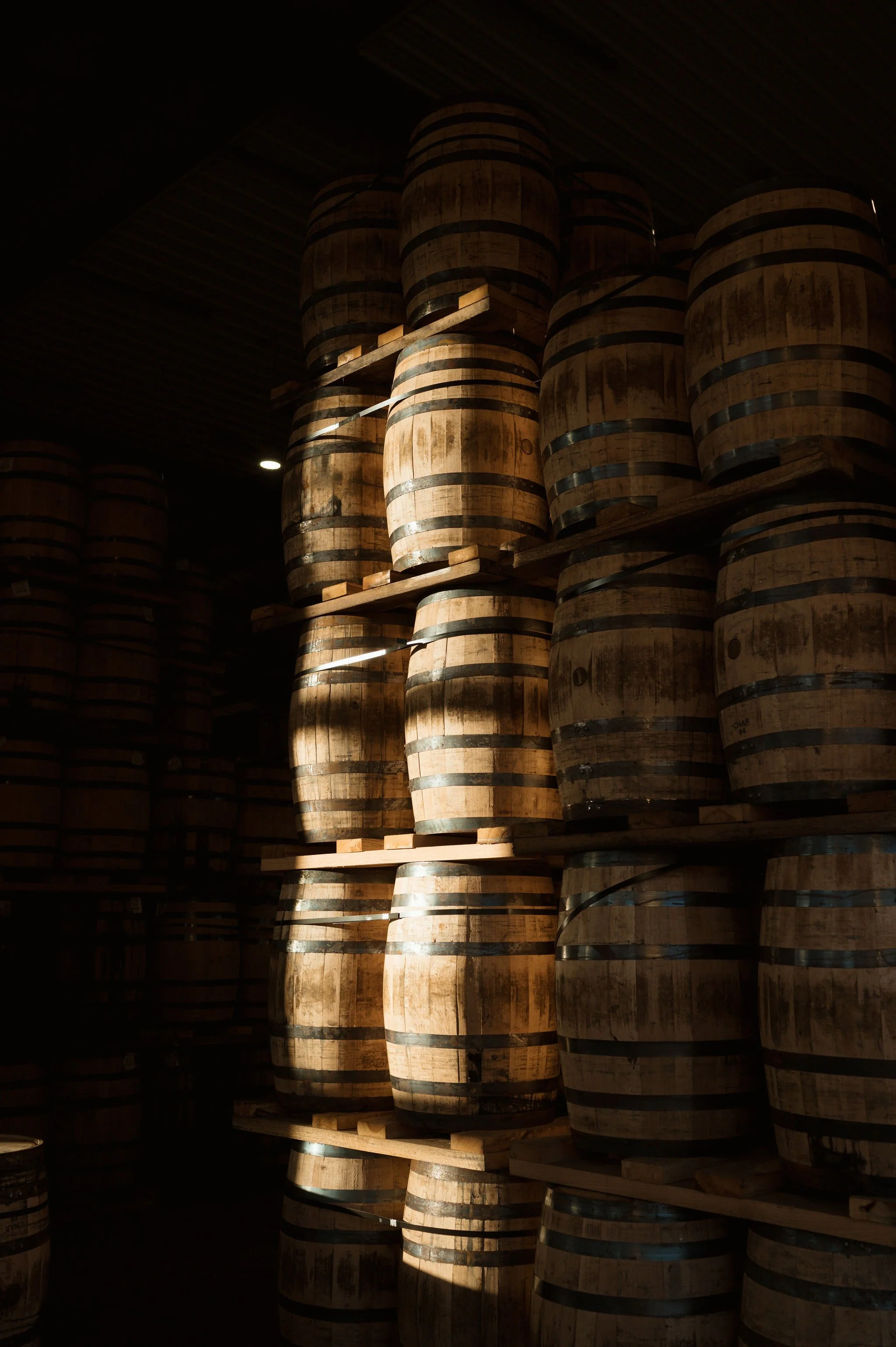 Stacks of wooden barrels stored in a warehouse.