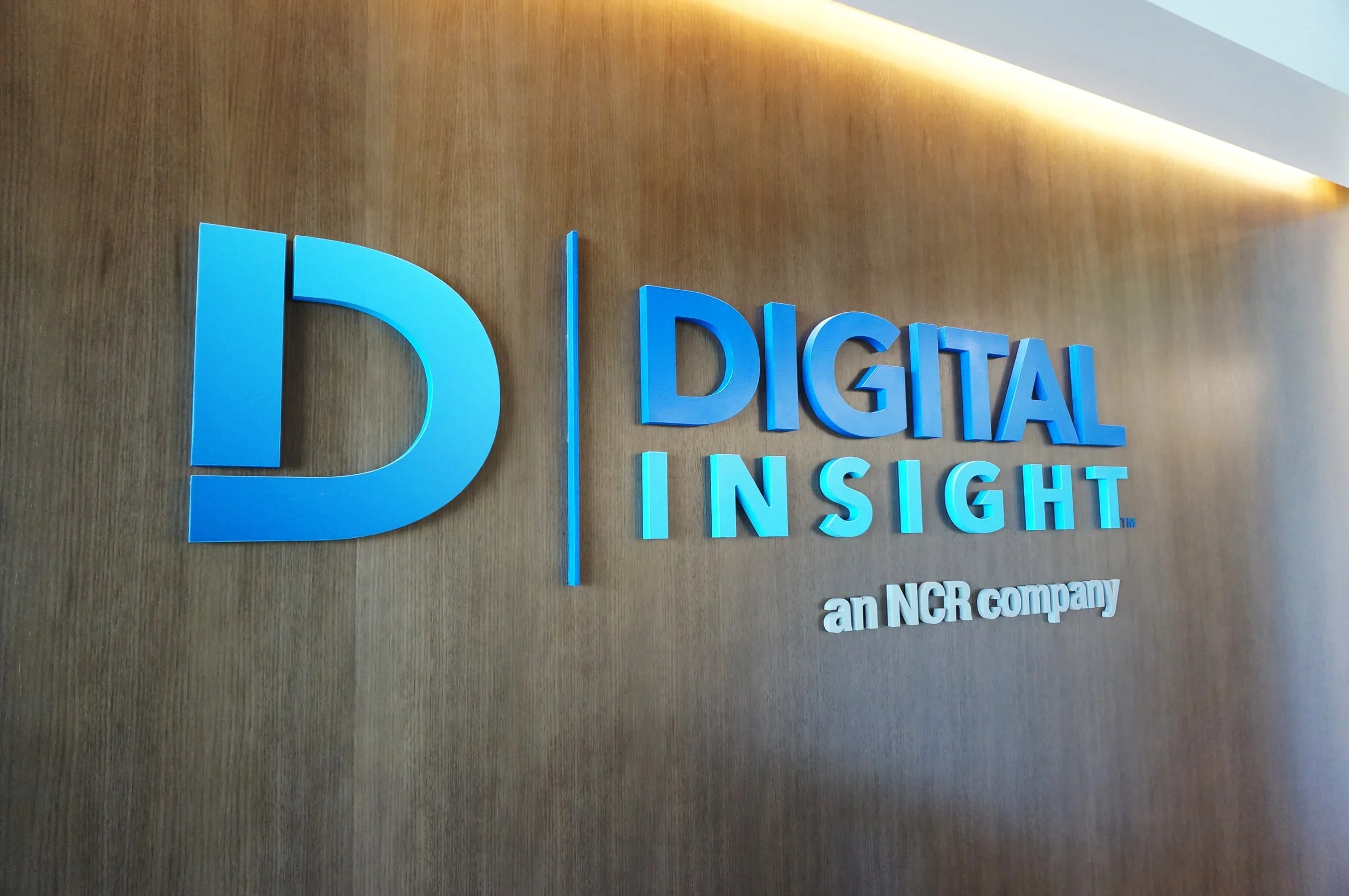 Close-up of a wall with a blue sign reading 'Digital Insight' and a smaller tagline below, part of NCR company branding.