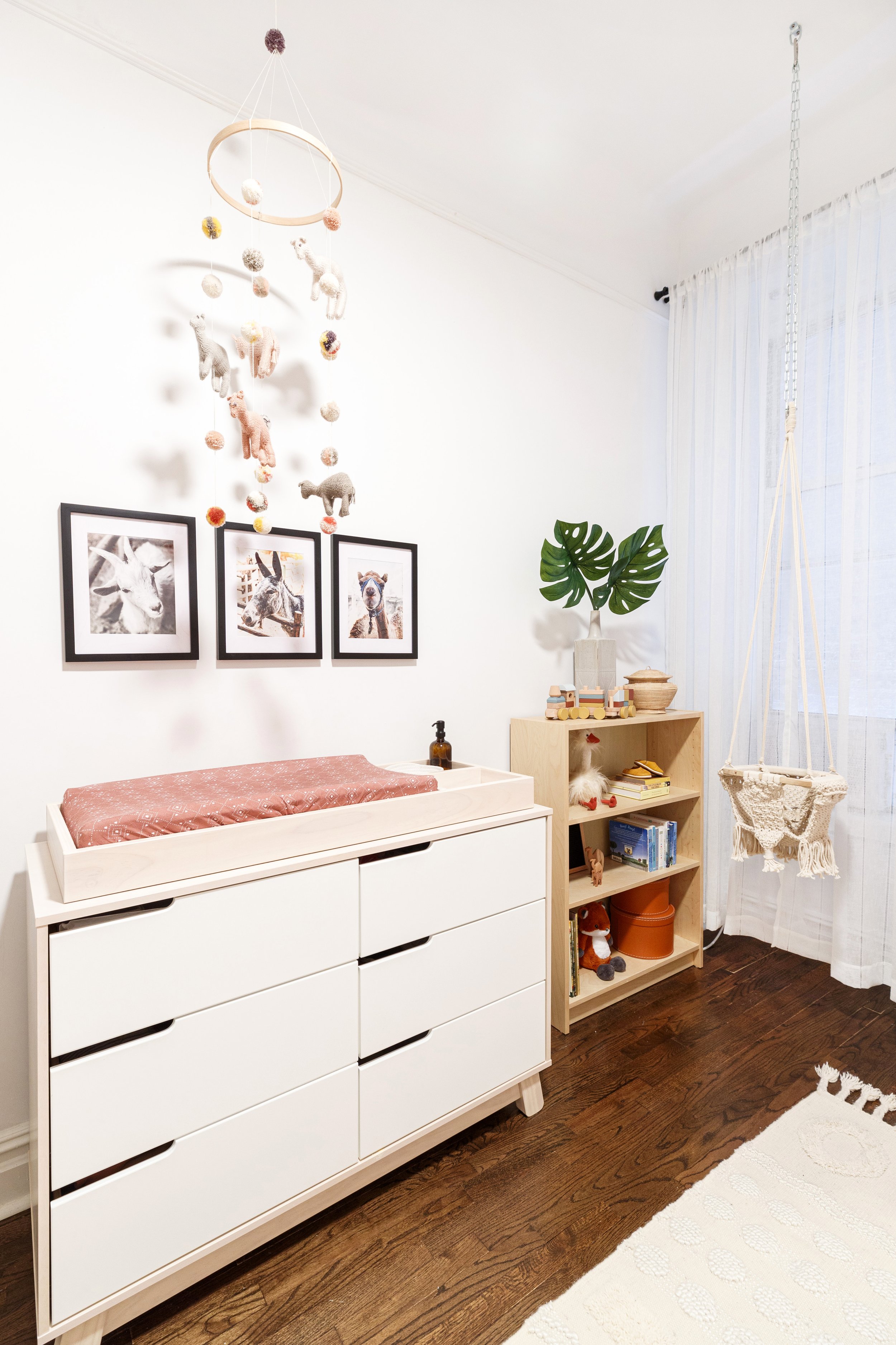 white and wood changing table and light wood bookshelf in Manhattan modern boho baby girl nursery designed by Westchester interior decorator Jordana Ross Interiors