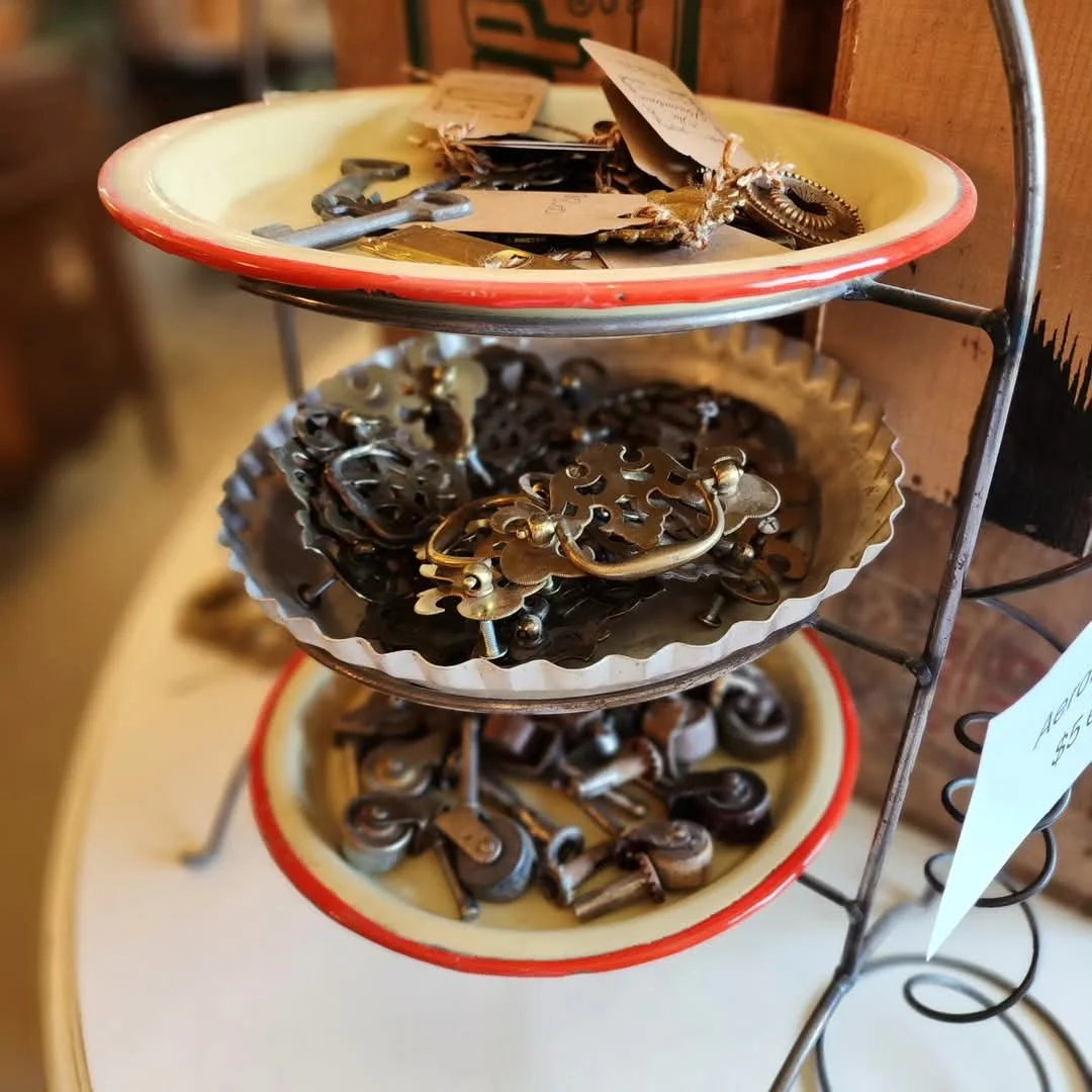 Three metal trays filled with jewelry and keys on a multi-tiered rack display.