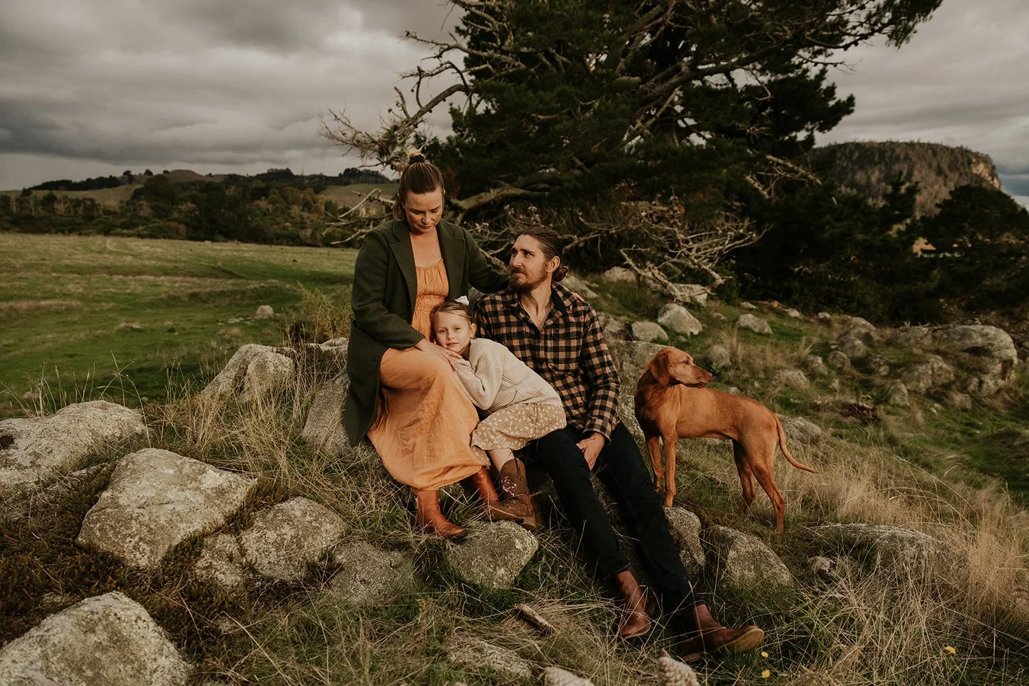 Family sitting on rock with there family dog embracing her daughter