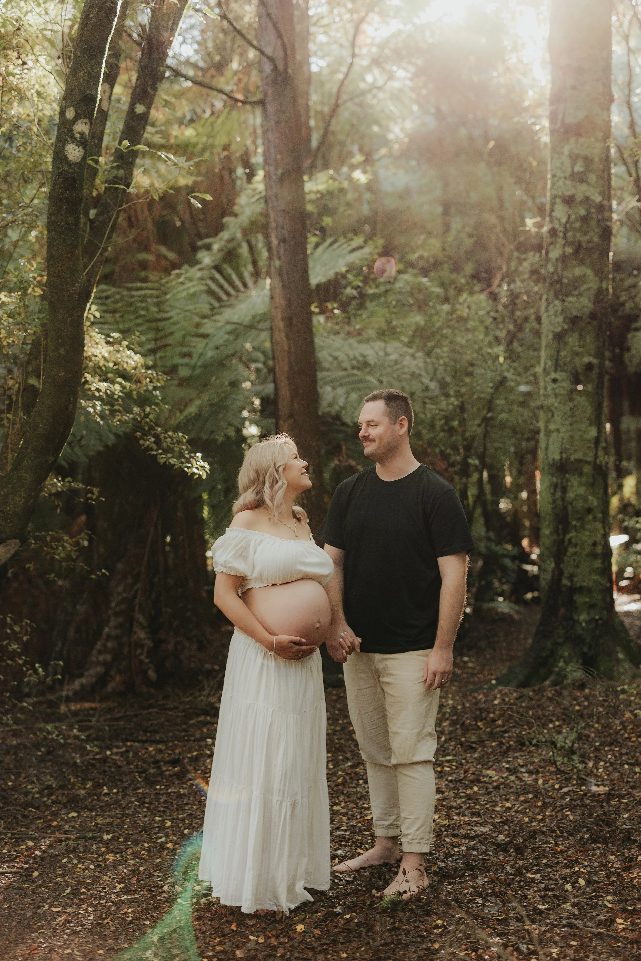 Expecting mother and partner standing in forrest