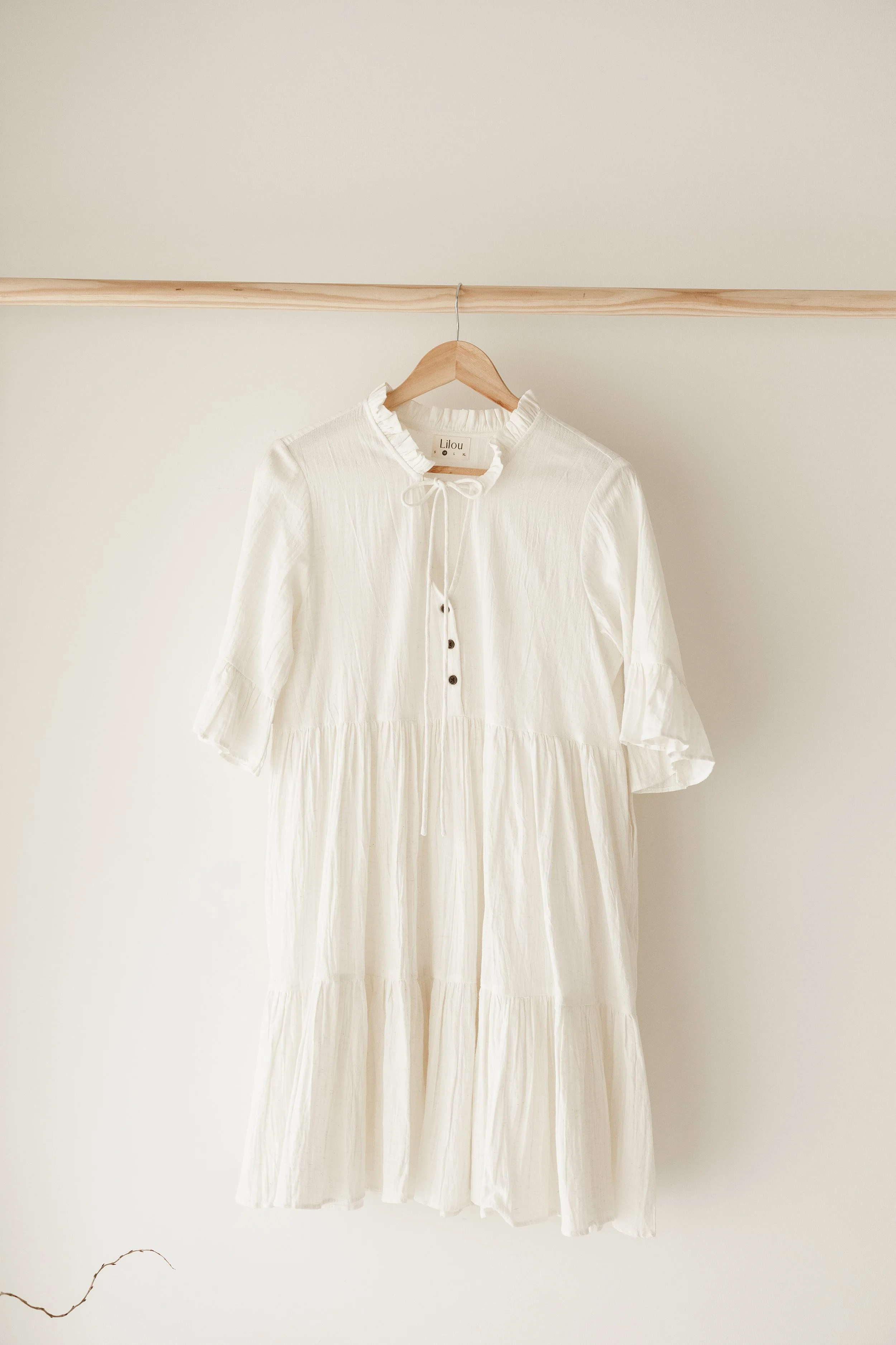 Cream coloured dress hanging inside a natural light studio space