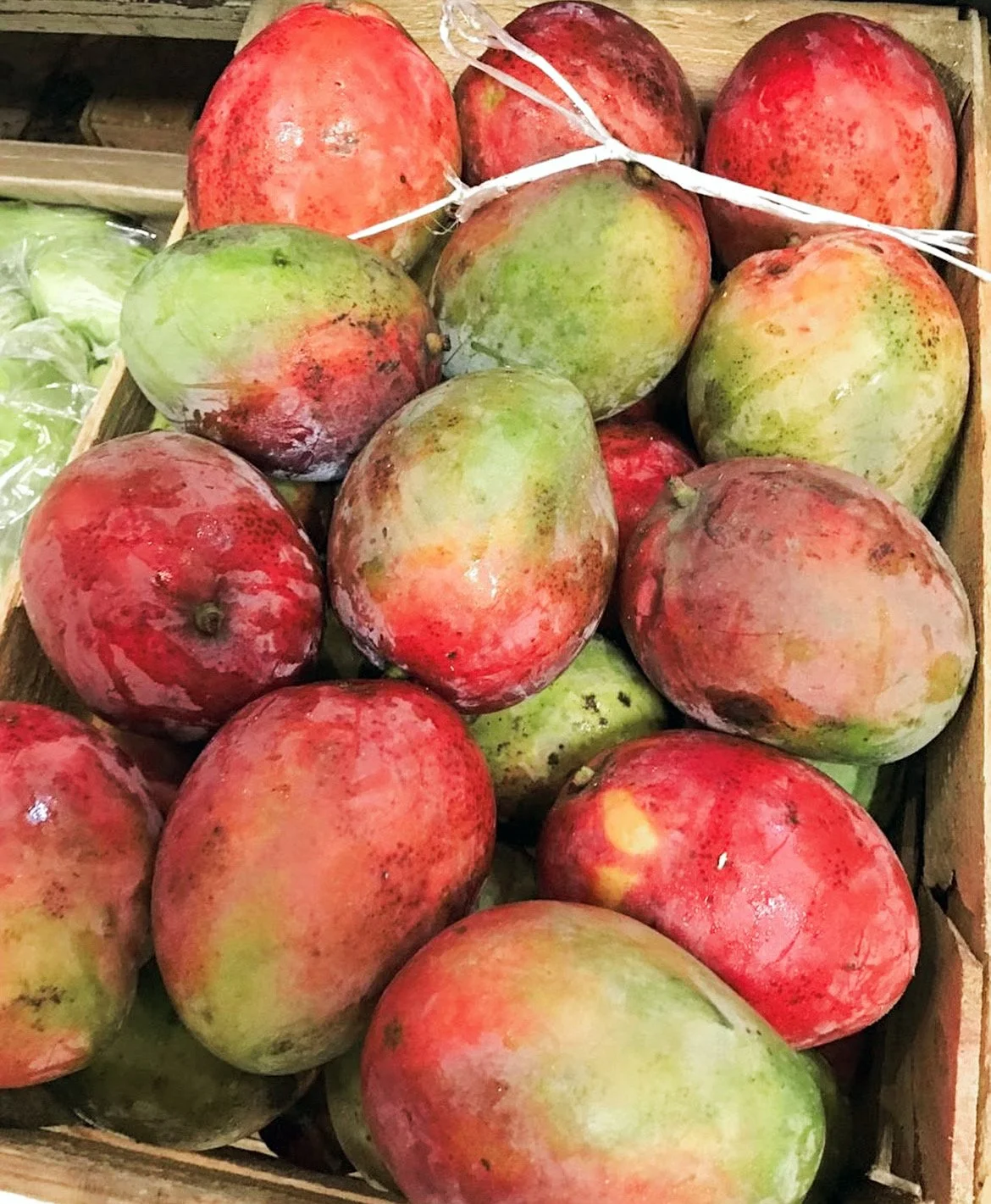Fresh ripe mangoes piled in a wooden crate.