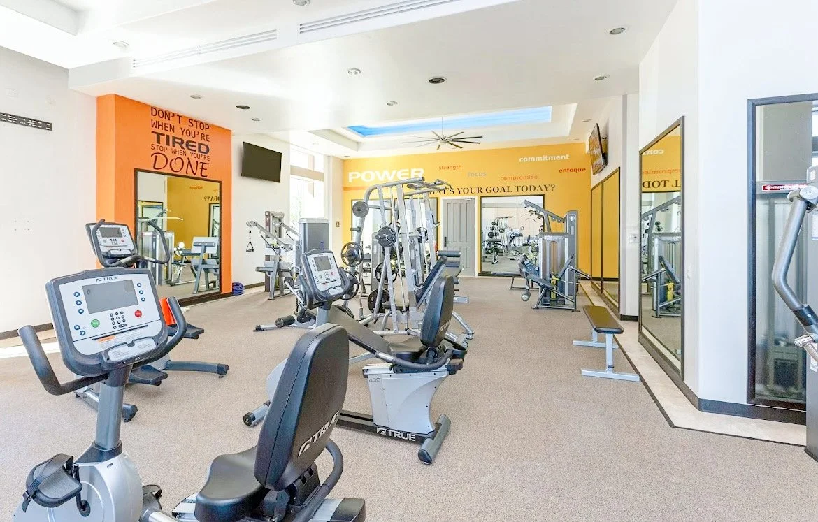 Modern gym interior with exercise equipment and motivational quotes on the walls.