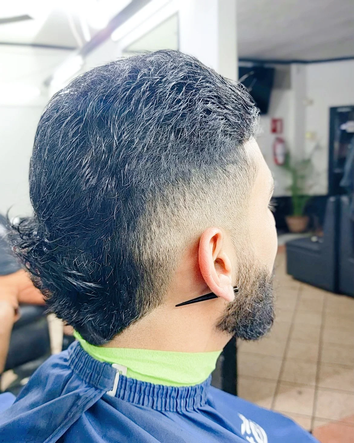 Man with a fresh haircut featuring a fade, in a barber shop setting.