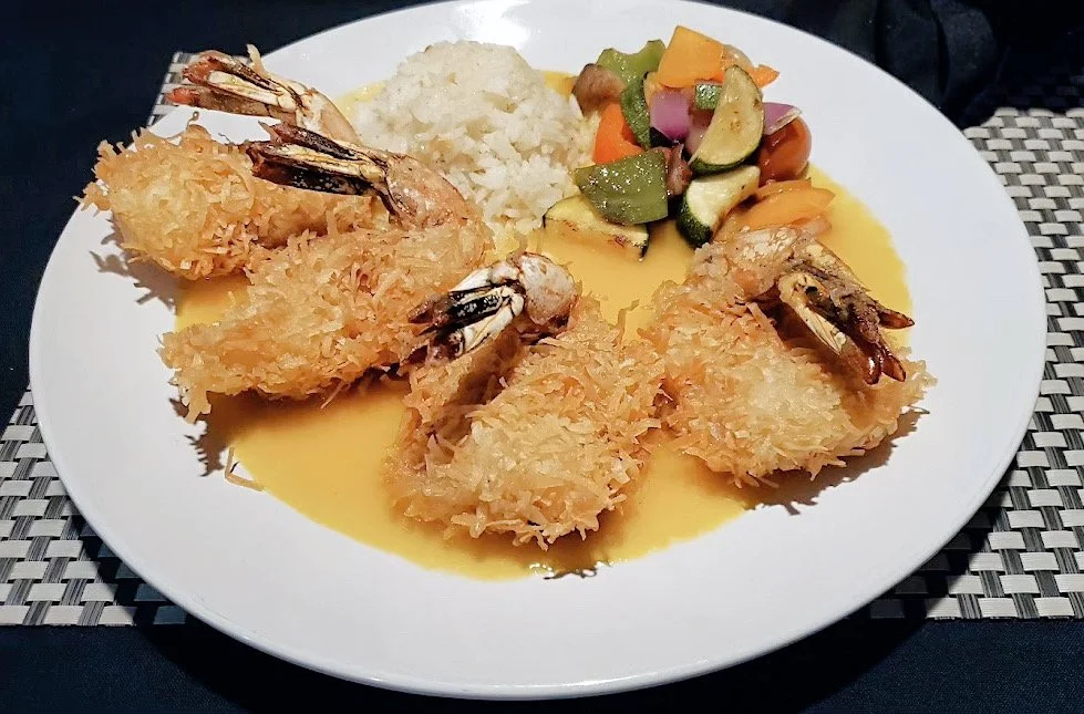 Plate with coconut shrimp, rice, mixed vegetables, and yellow sauce.
