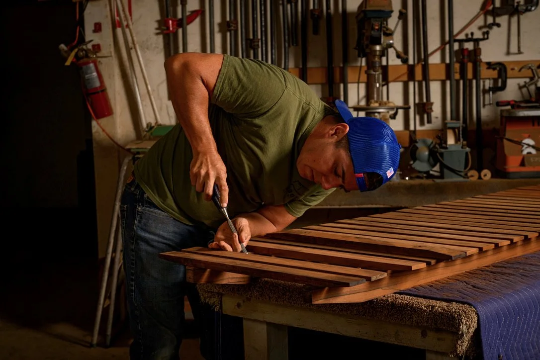Aaron Moore working on a slatted wood piece at the bench in his shop