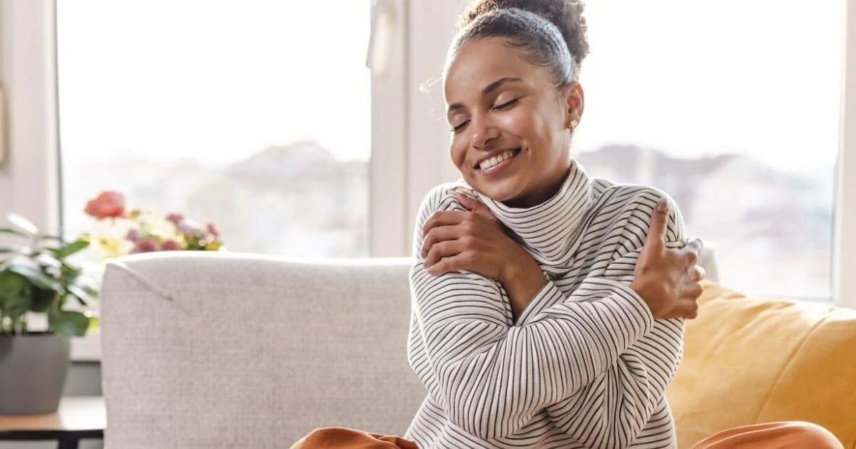 A woman hugging herself and happy, she is practicing christian counseling for self worth.
