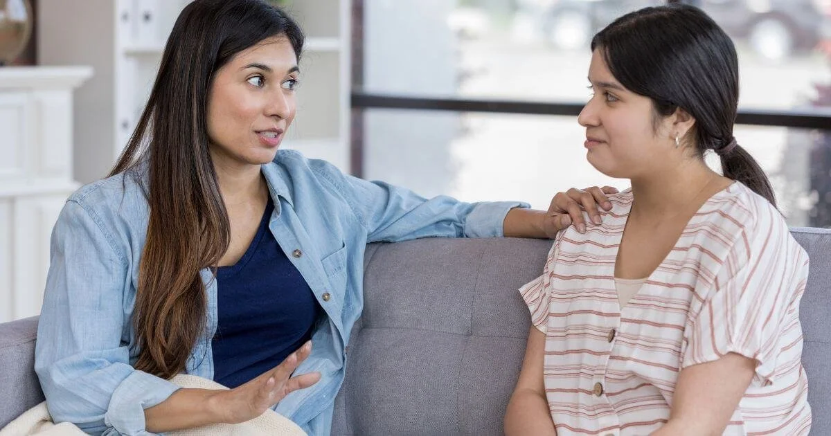 Two women having a supportive conversation on a couch representing Christian therapy for boundaries and healthy communication