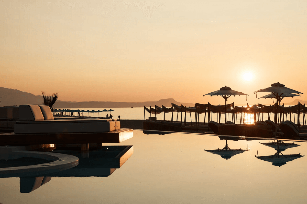 Dreamy sunset glow over the pool and sunbeds at Uzenie All-Suites Boutique Resort, Crete 2026 – umbrellas and calm sea views for ultimate relaxation.