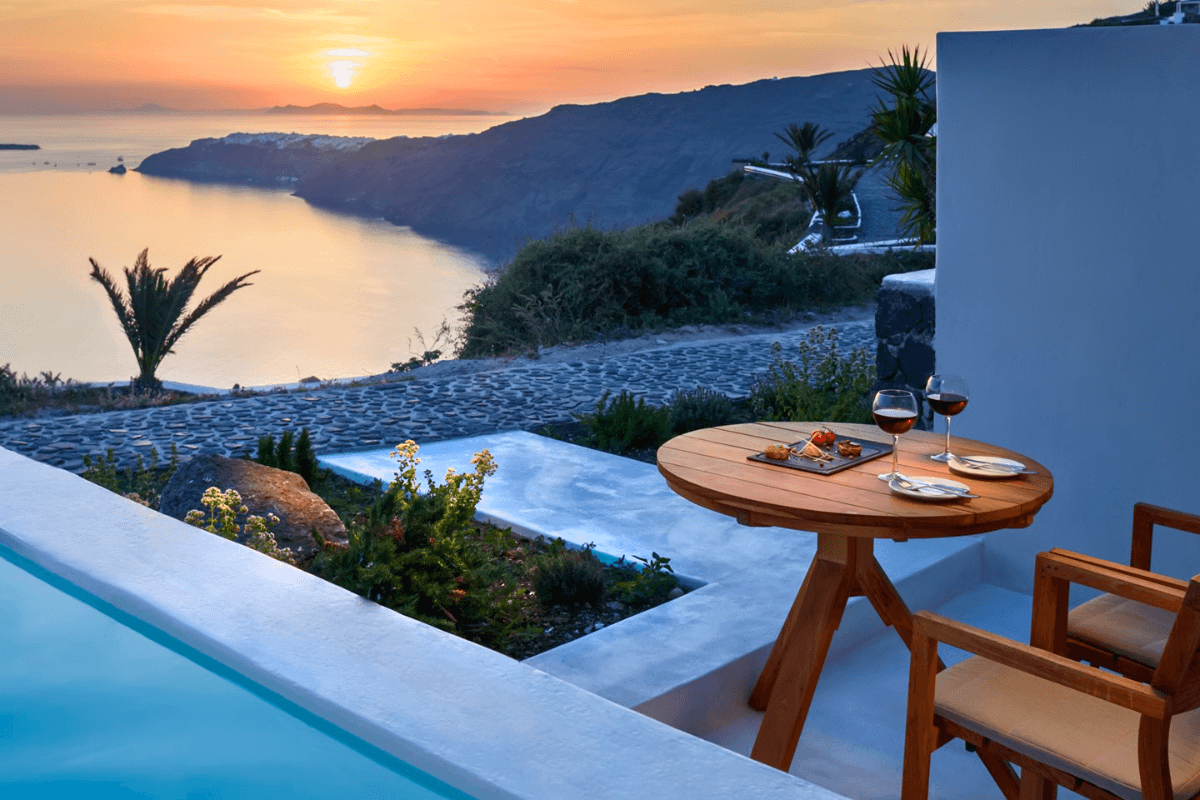 Xenones Filotera terrace in Imerovigli at sunset with pool, sea views, and the Santorini caldera