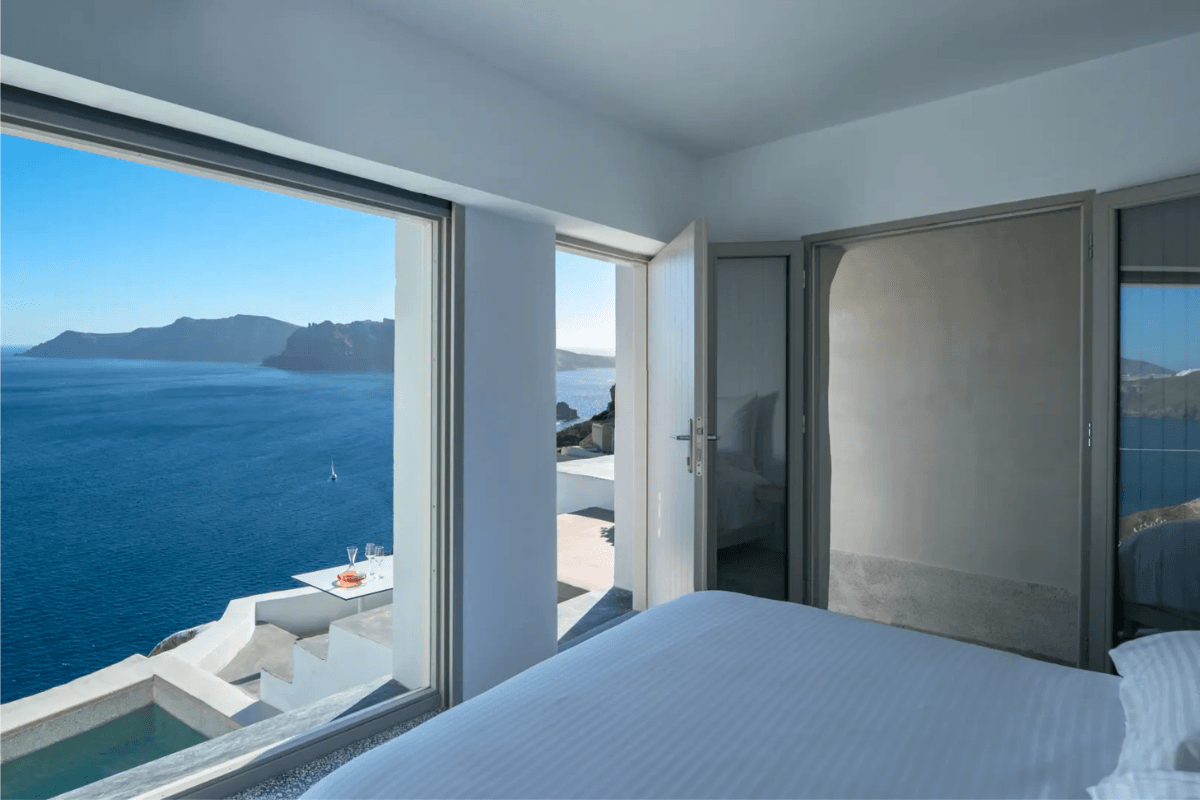 Echoes Suite in Oia with a caldera view from the bed, terrace, and private plunge pool