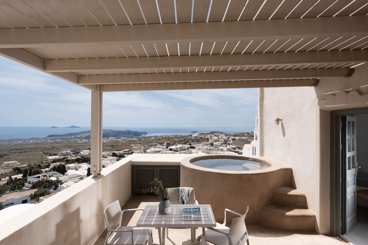 Private terrace with hot tub at Kastro Mansion in Pyrgos, Santorini, showcasing stunning Caldera and village views.