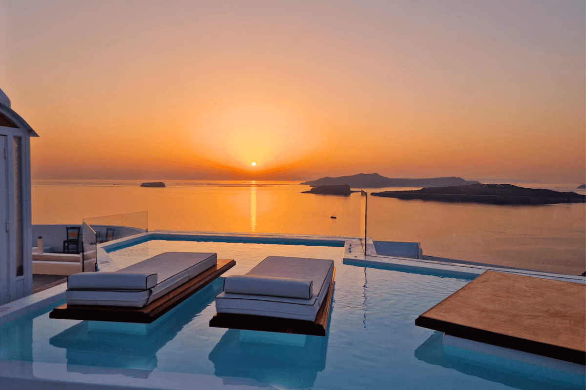 Private overflow pool with panoramic caldera views at sunset in Santorini