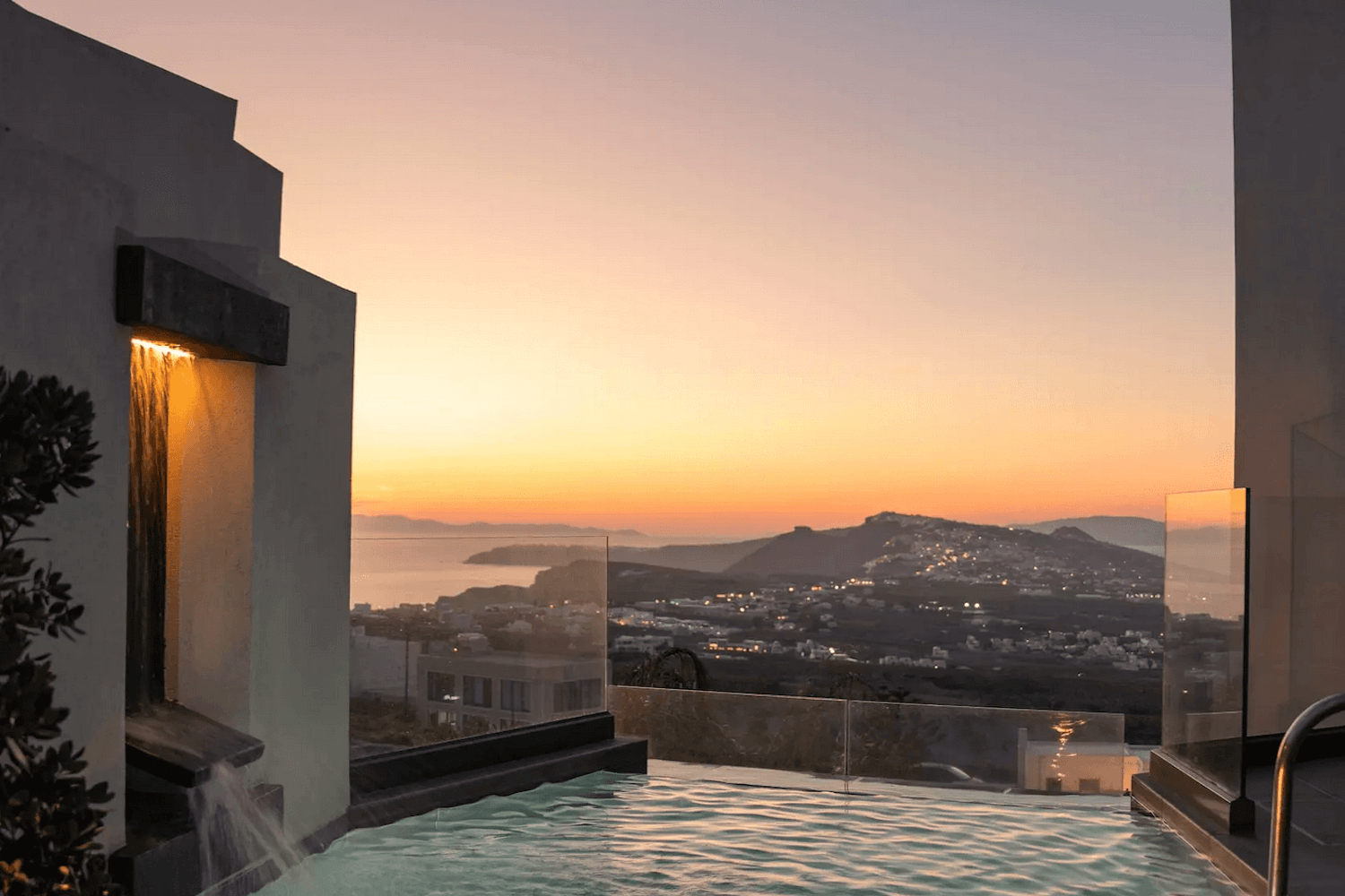 Boutique pool with Caldera views at Apikia Santorini Hotel in Pyrgos, Santorini, glowing at sunset during golden hour.