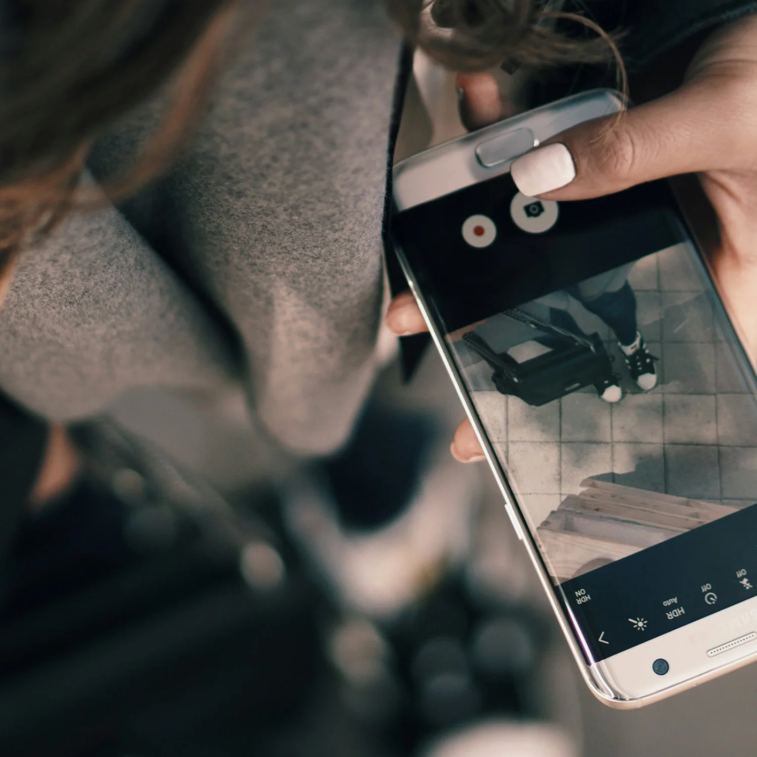 A hand holding an iphone to capture what she is wearing
