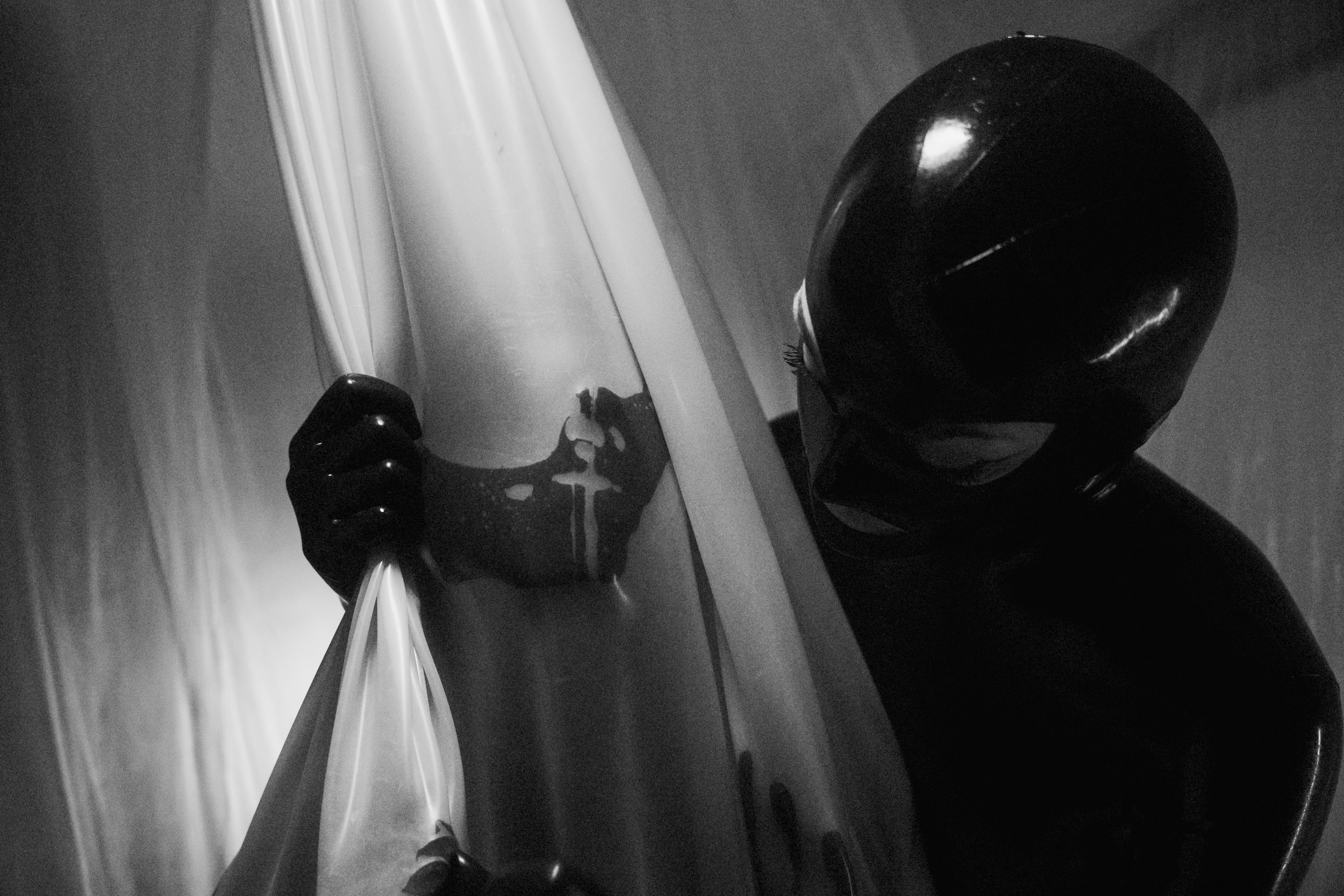 A person wearing a shiny helmet and gloves peering into a reflective surface.