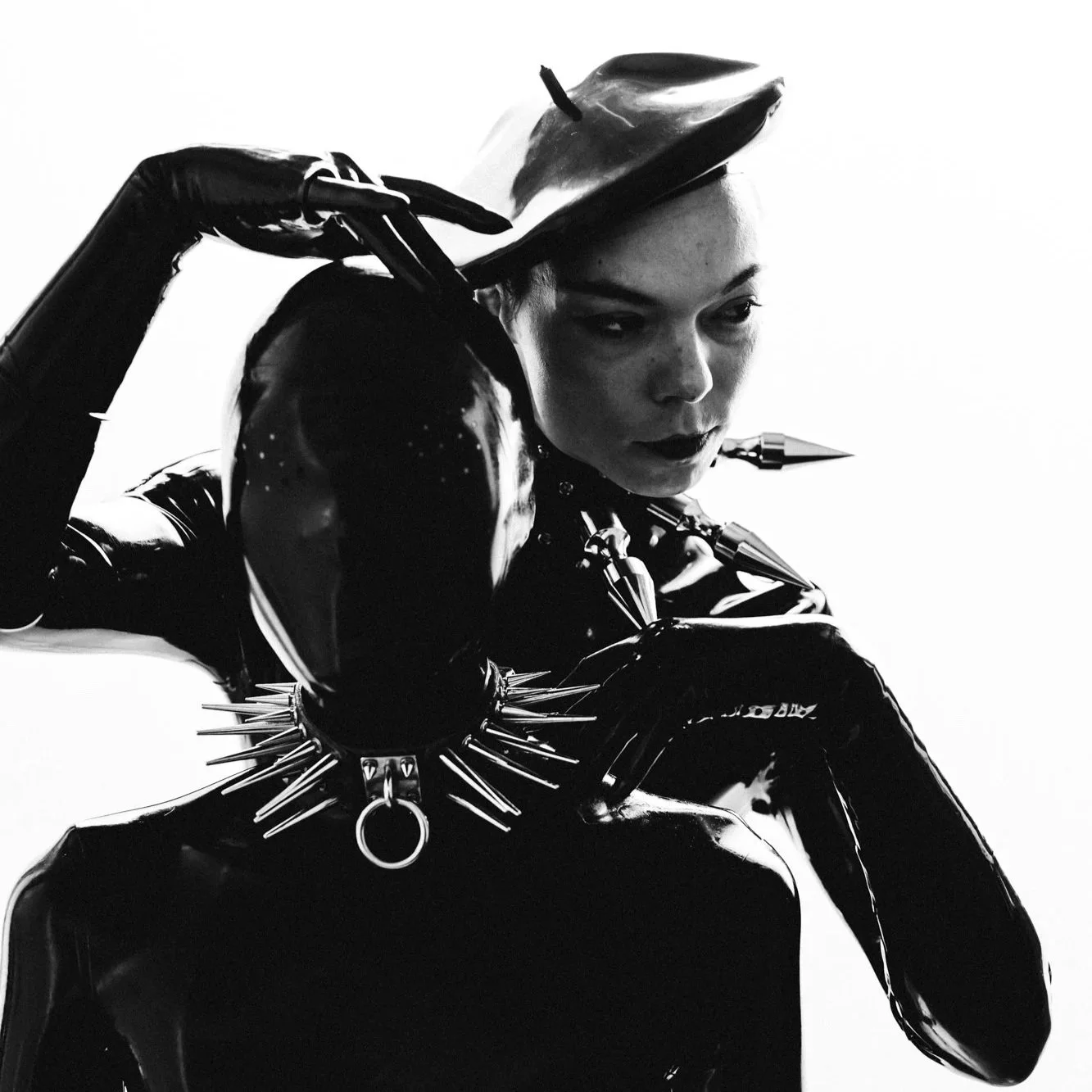 Modern wooden house with large glass window, set against a mountainous landscape, with grassy terrain and sparse trees in the foreground.