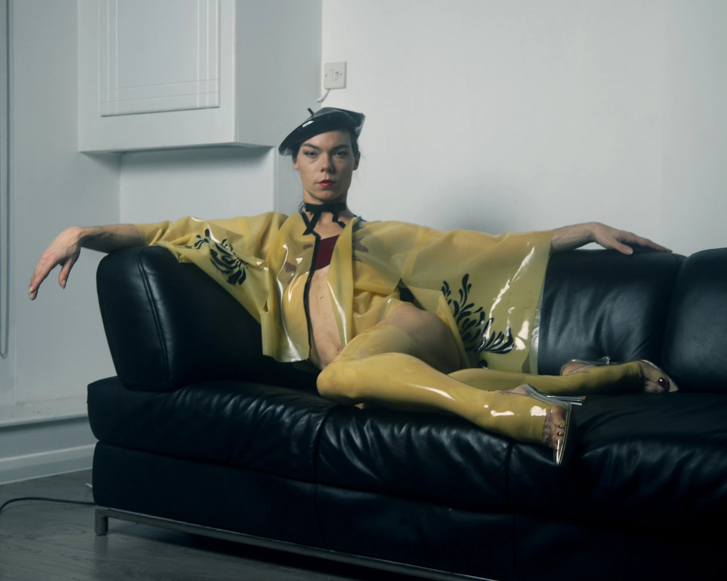 Modern building on green hills with snow-capped mountains in the background under cloudy sky.