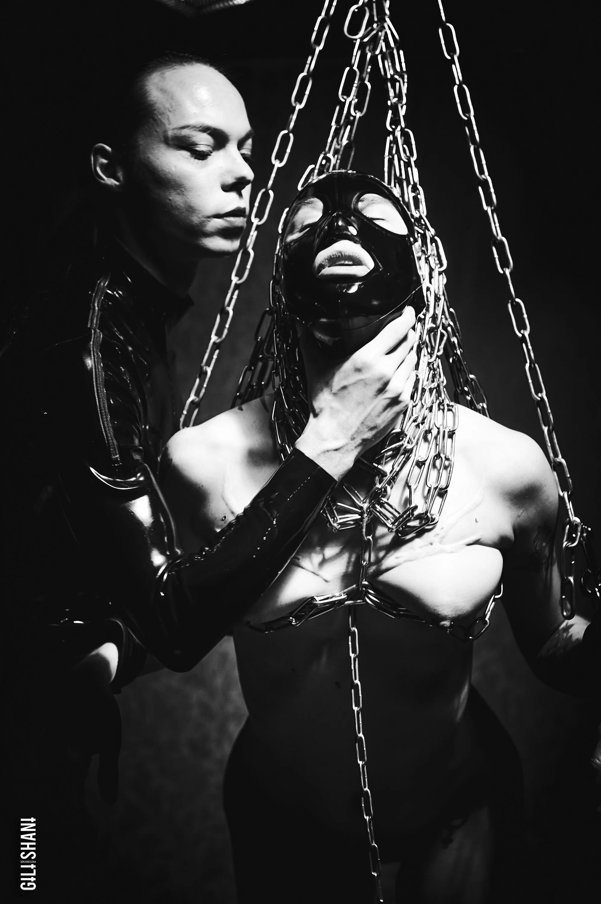 Scenic landscape of a lake surrounded by green hills and tall mountains under an overcast sky.