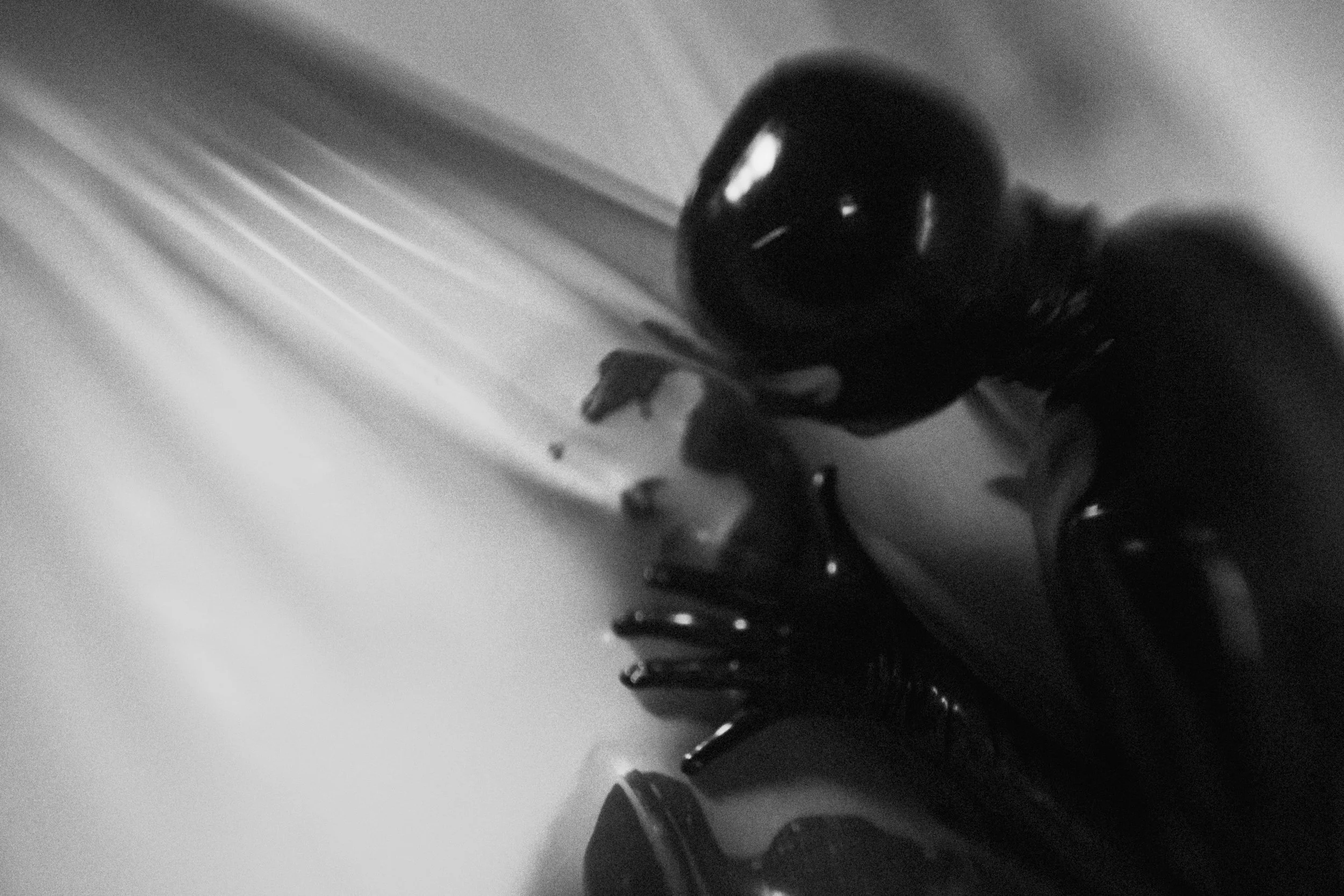 Close-up of a person's hand wearing a glove, holding an object near a metallic surface with light reflections.