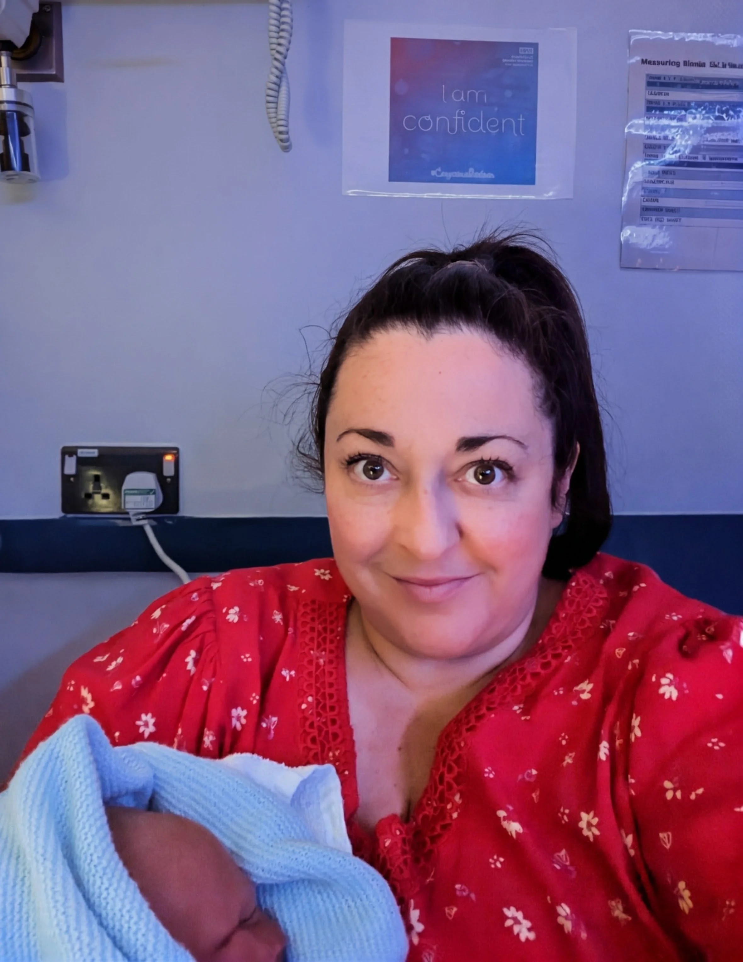 Doula Jemma holding and caring for newborn baby whilst the new mother takes her first shower supported by her husband.