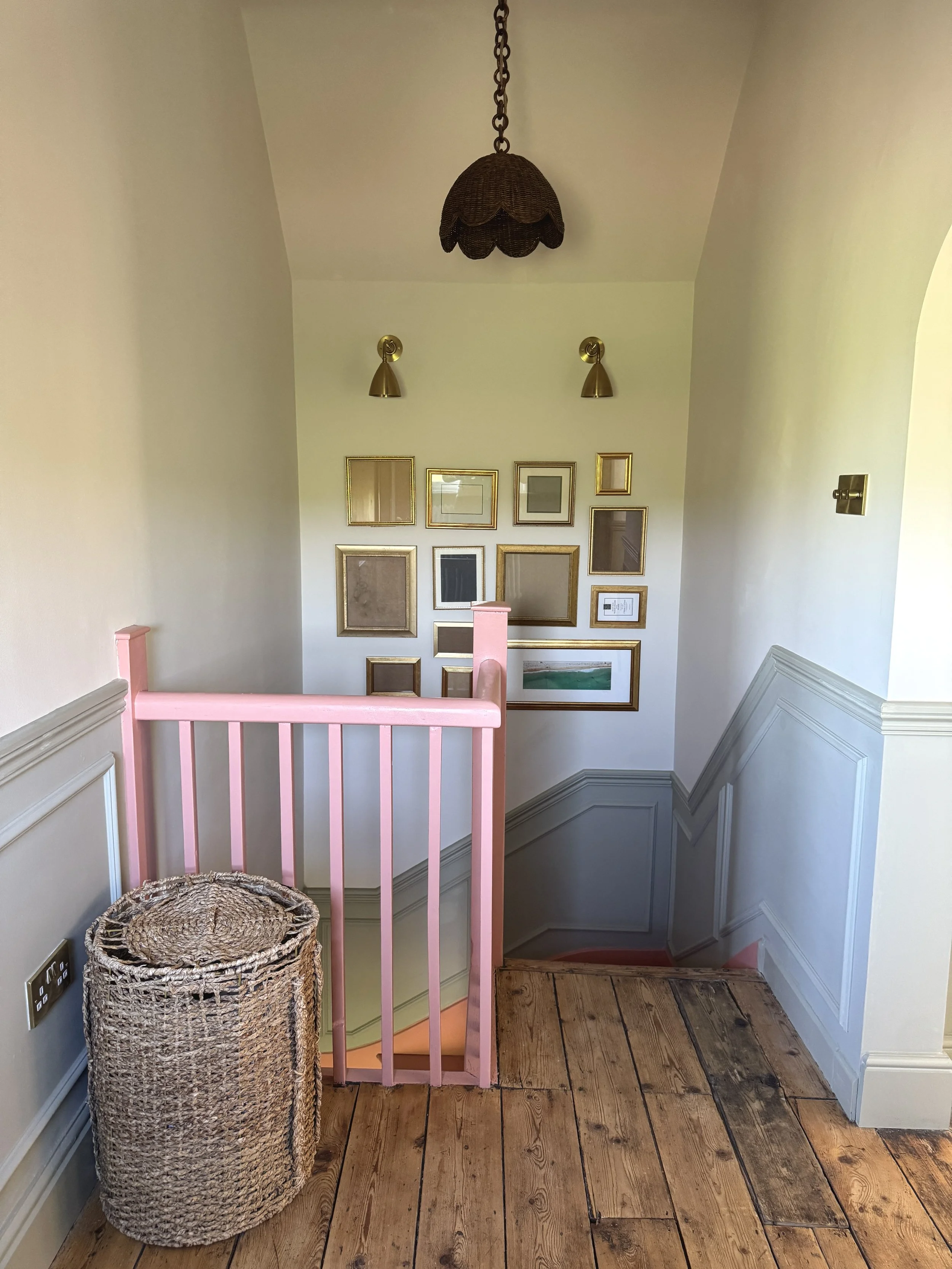 Staircase gallery wall with vintage frames, painted balustrade and original timber floorboards.