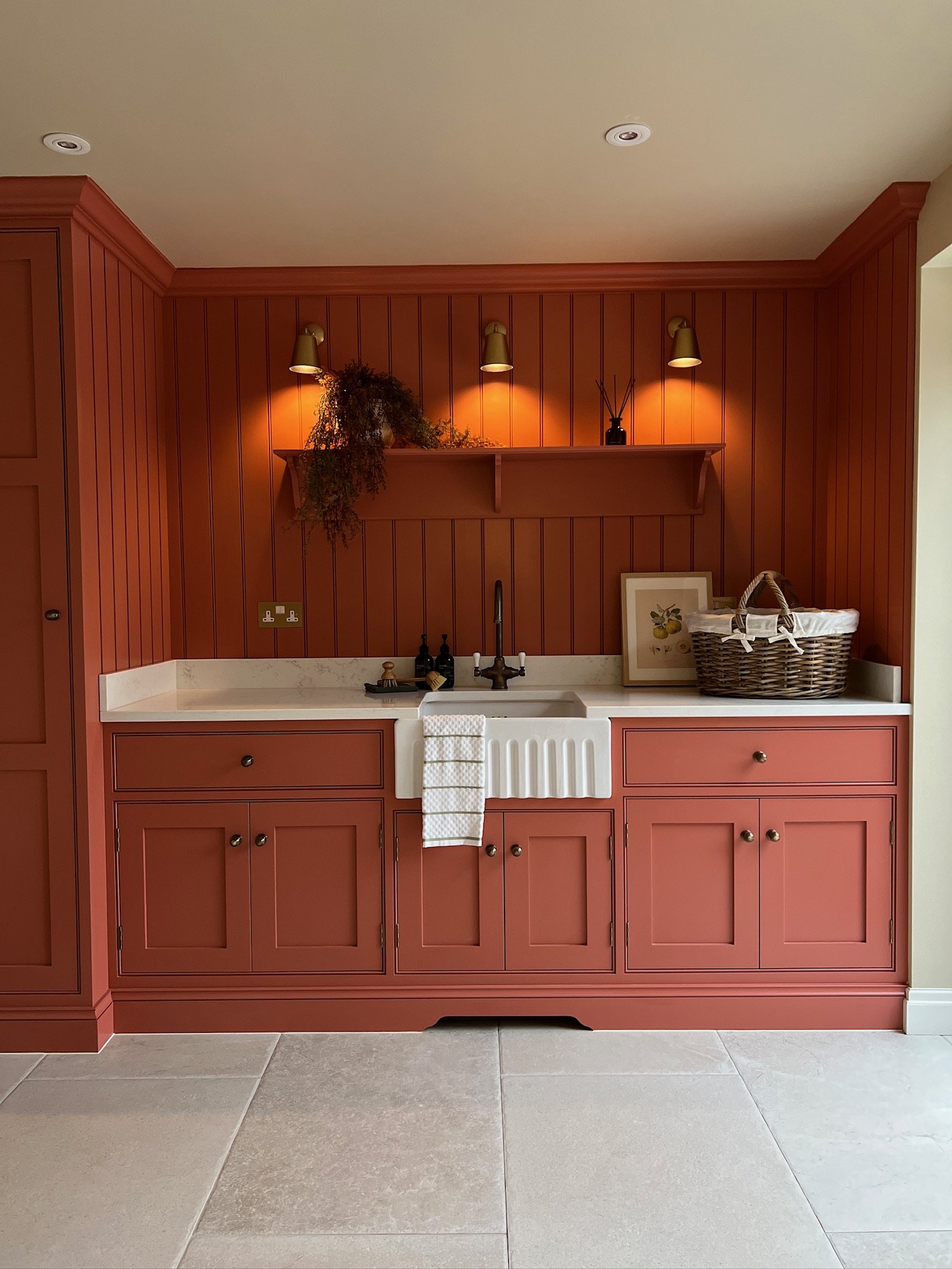 Mediterranean-inspired utility room featuring terracotta cabinetry, brass lighting and a farmhouse sink in a bespoke West Midlands home by Istigh Interiors.