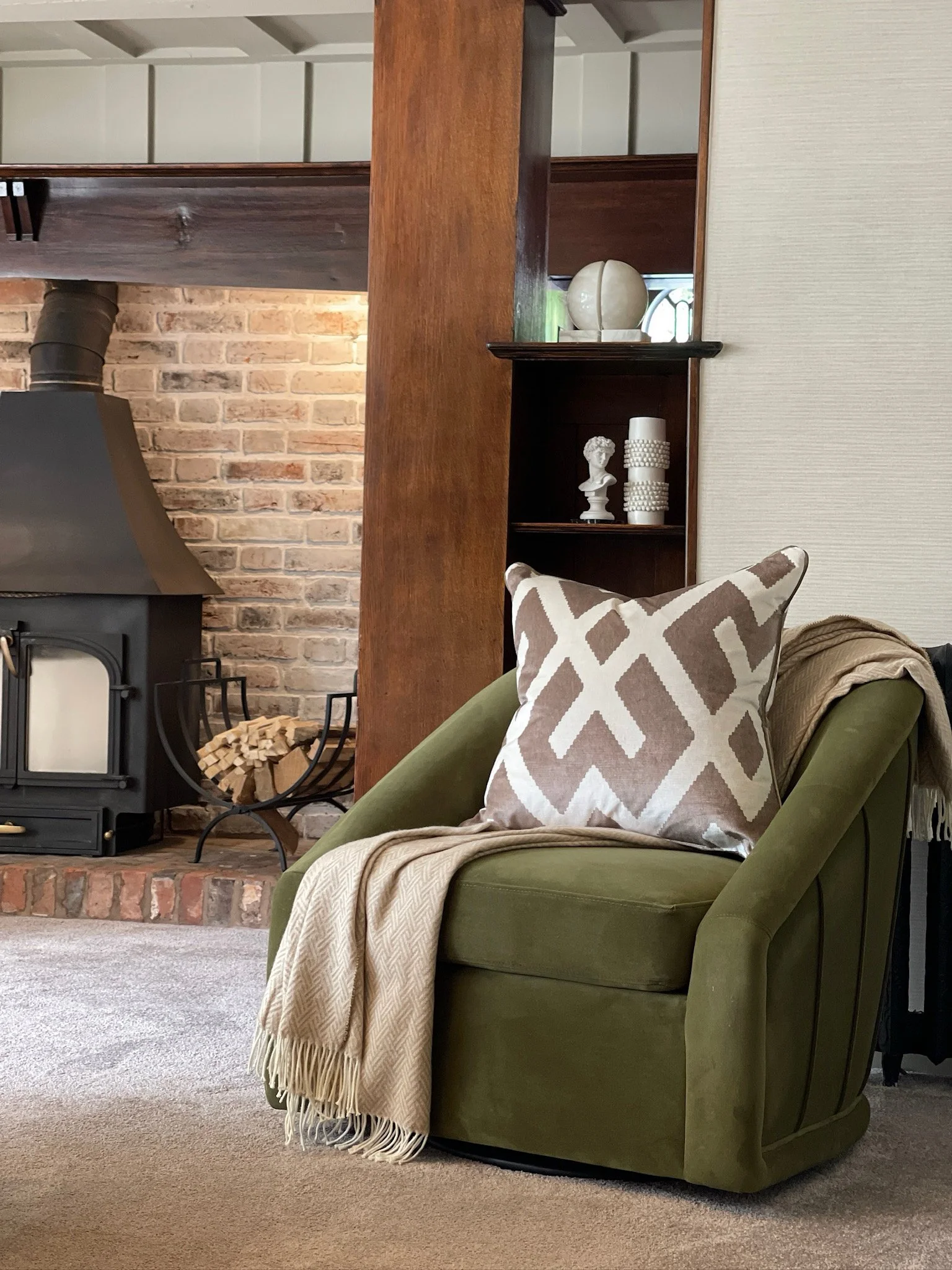 Olive green velvet accent chair styled beside the original brick fireplace in a Grade II listed family home renovation.