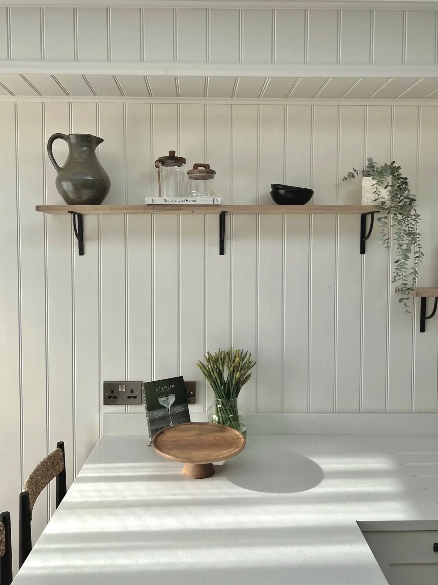 Open oak shelving set against shaker wall panelling in the bespoke kitchen at Project Brixham, Devon.