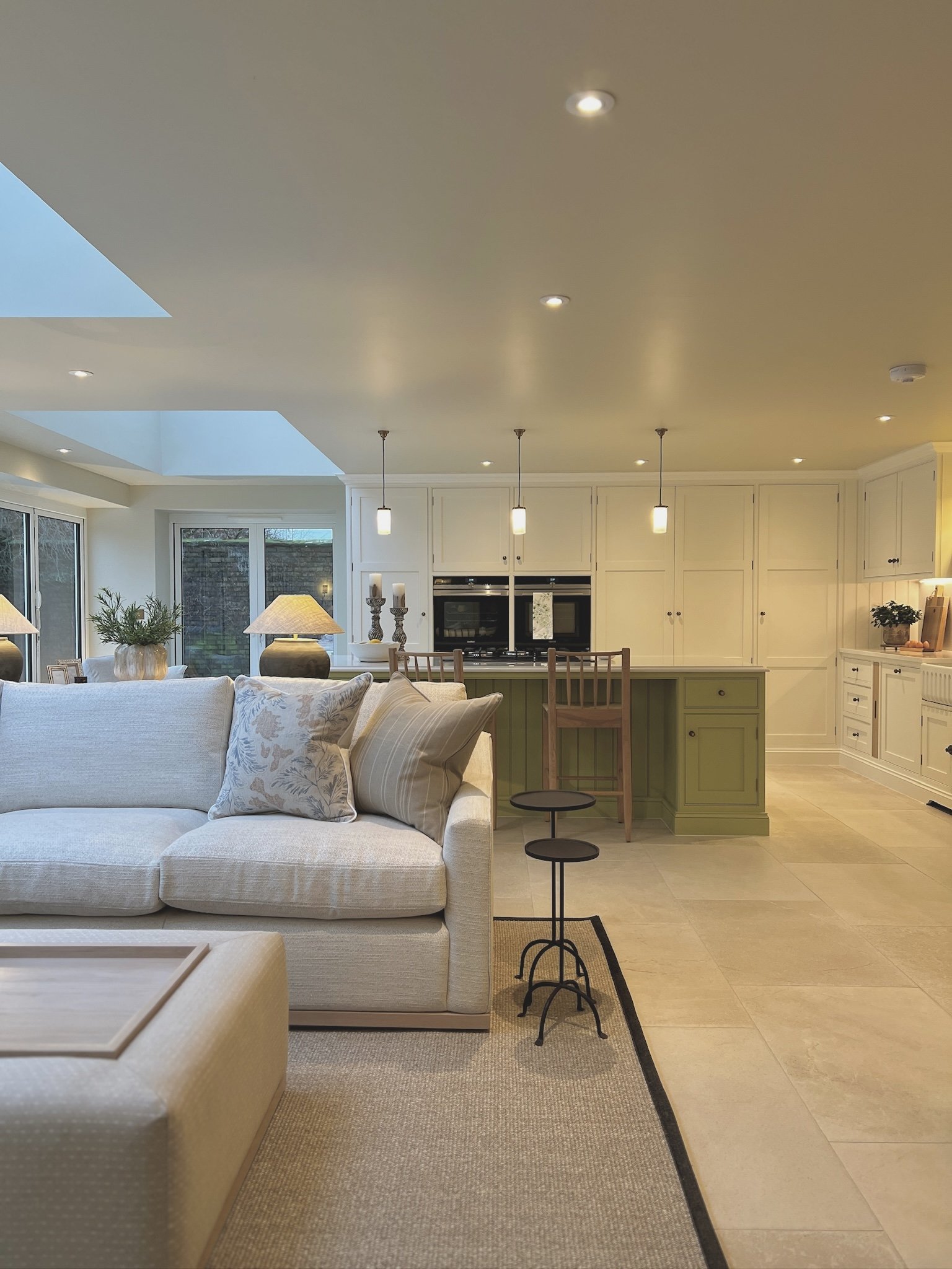 Open-plan kitchen and living space at Project Paddock featuring a bespoke sage green island, shaker cabinetry and soft neutral furnishings.