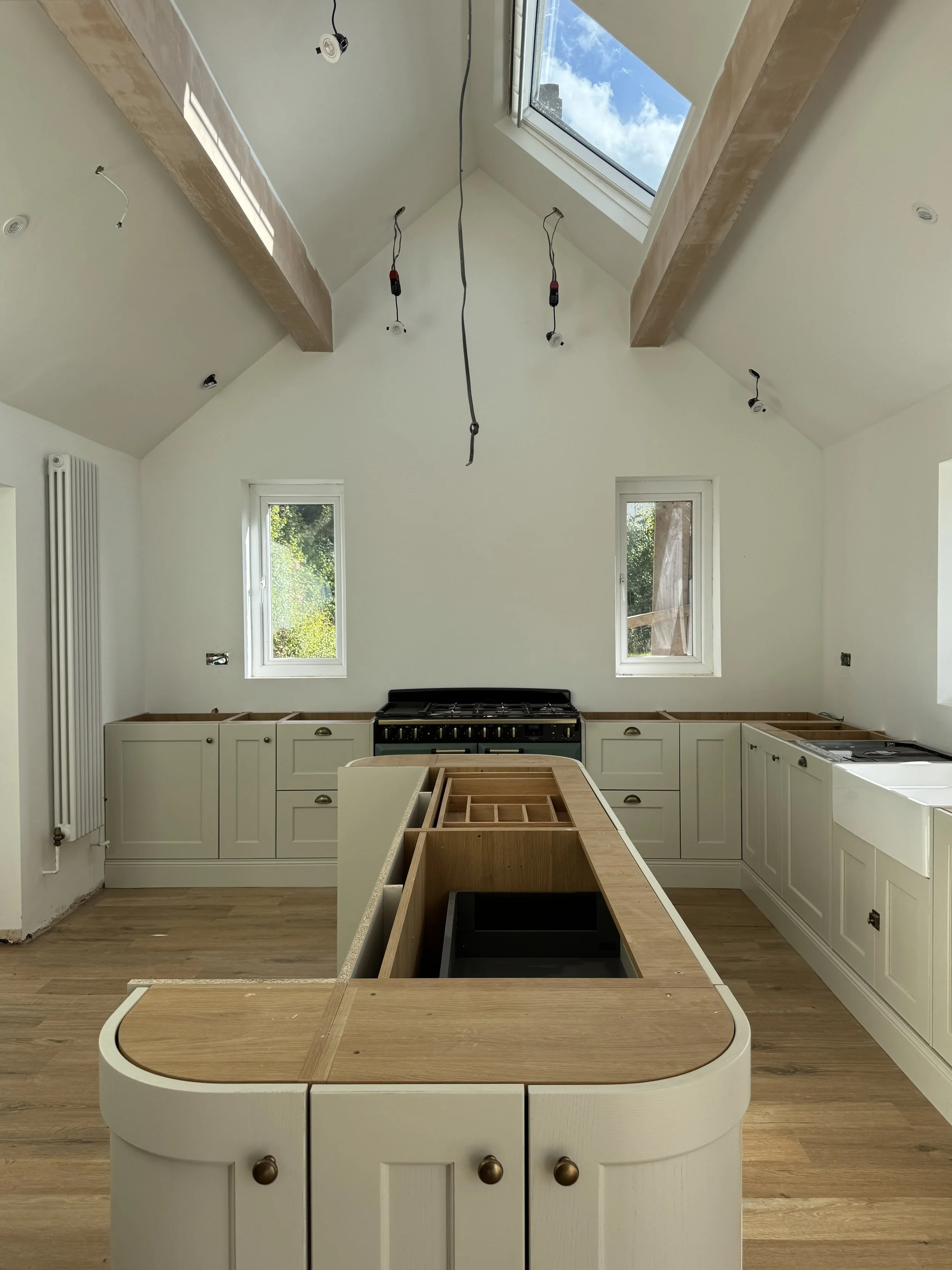 Painted shaker kitchen within a vaulted extension featuring quartz worktops, a large central island, traditional cabinetry and soft sage green cabinetry designed for modern family living.