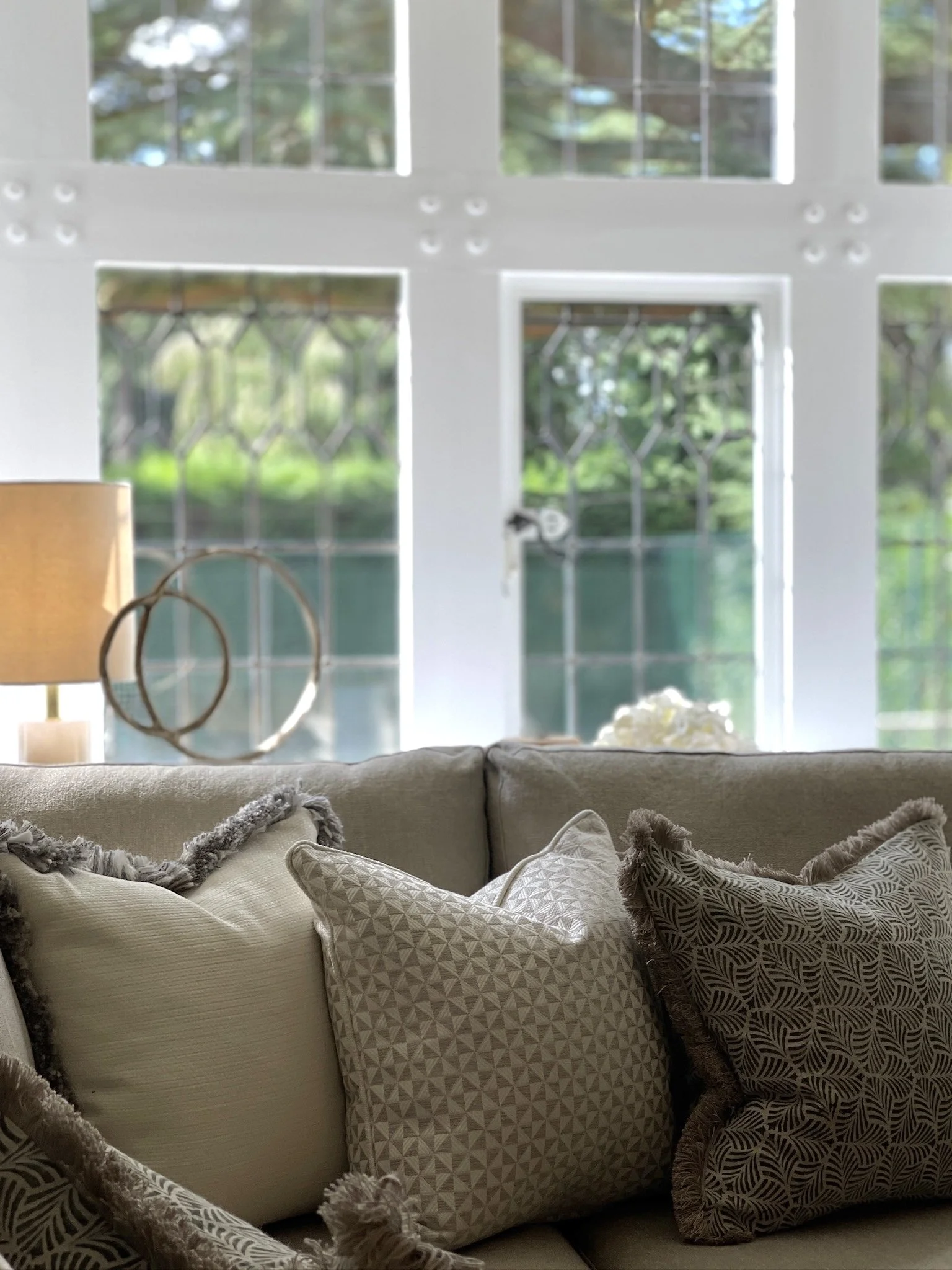 Close-up of layered neutral cushions on a bespoke sofa within the living room of a Grade II listed family home designed by Istigh Interiors.