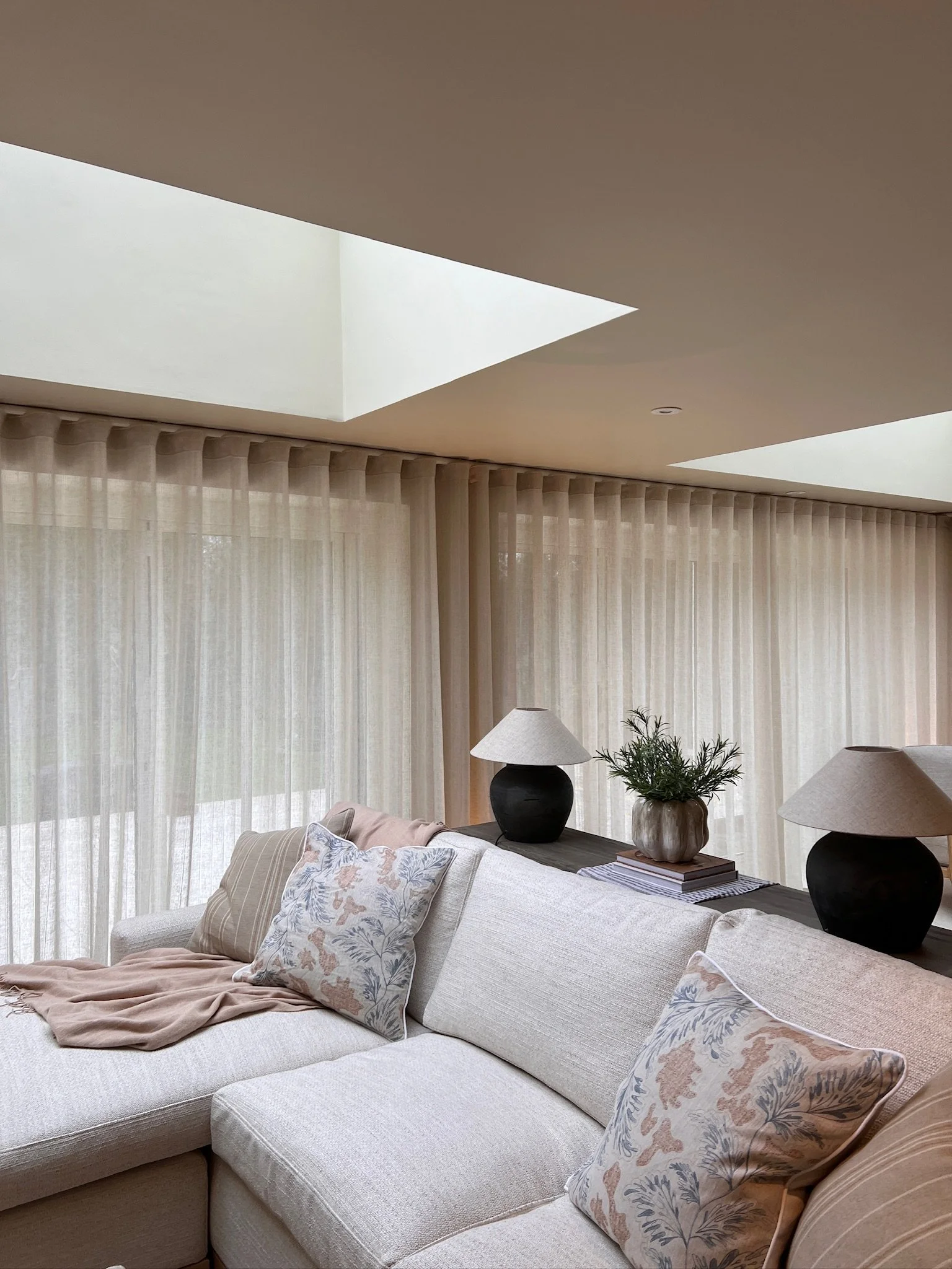 Soft linen sheer curtains and large roof lantern flooding the open-plan living area with natural light.