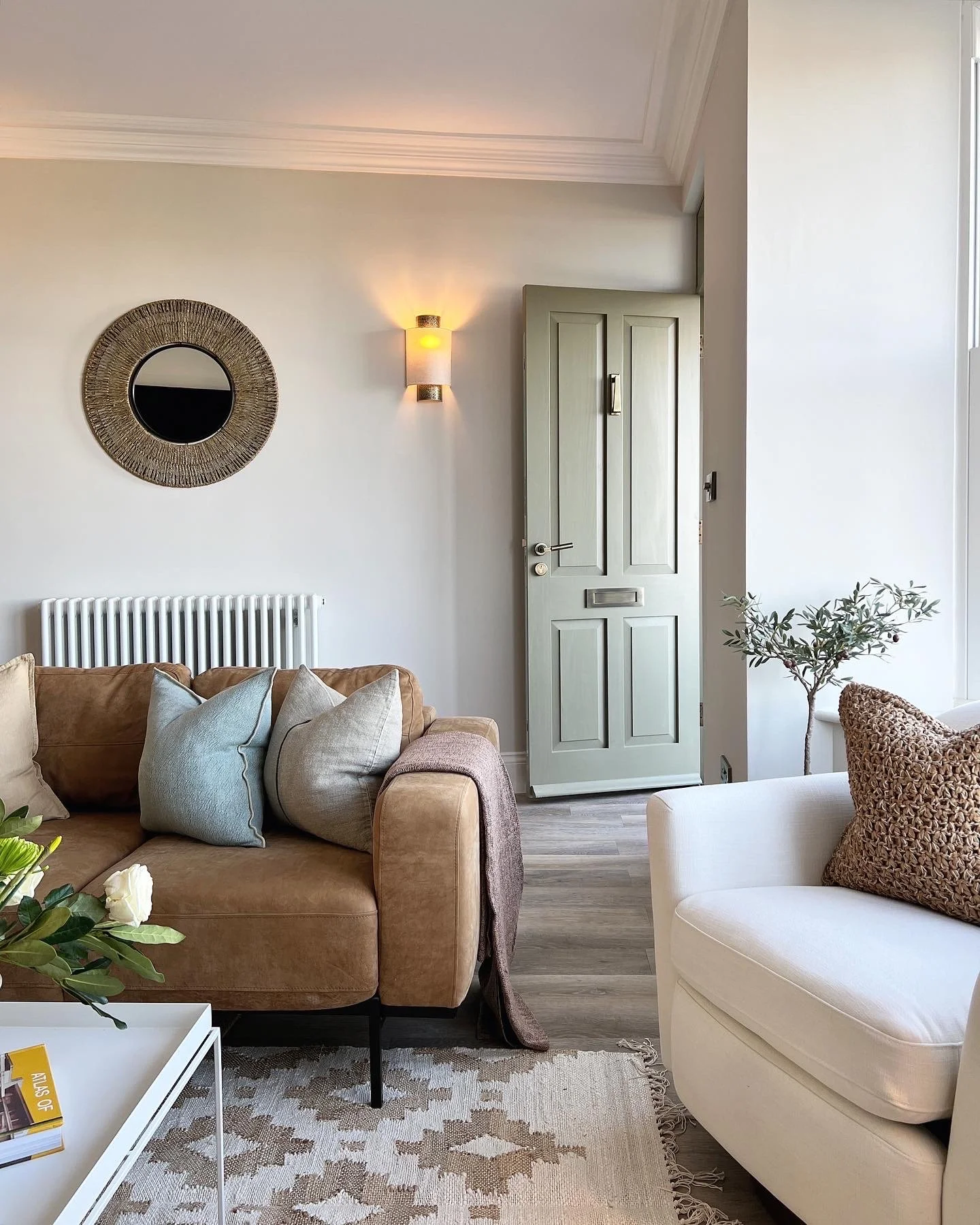 Sitting room in Project Brixham, Devon, featuring a sage green front door, soft neutral furnishings and natural textures by Istigh Interiors.