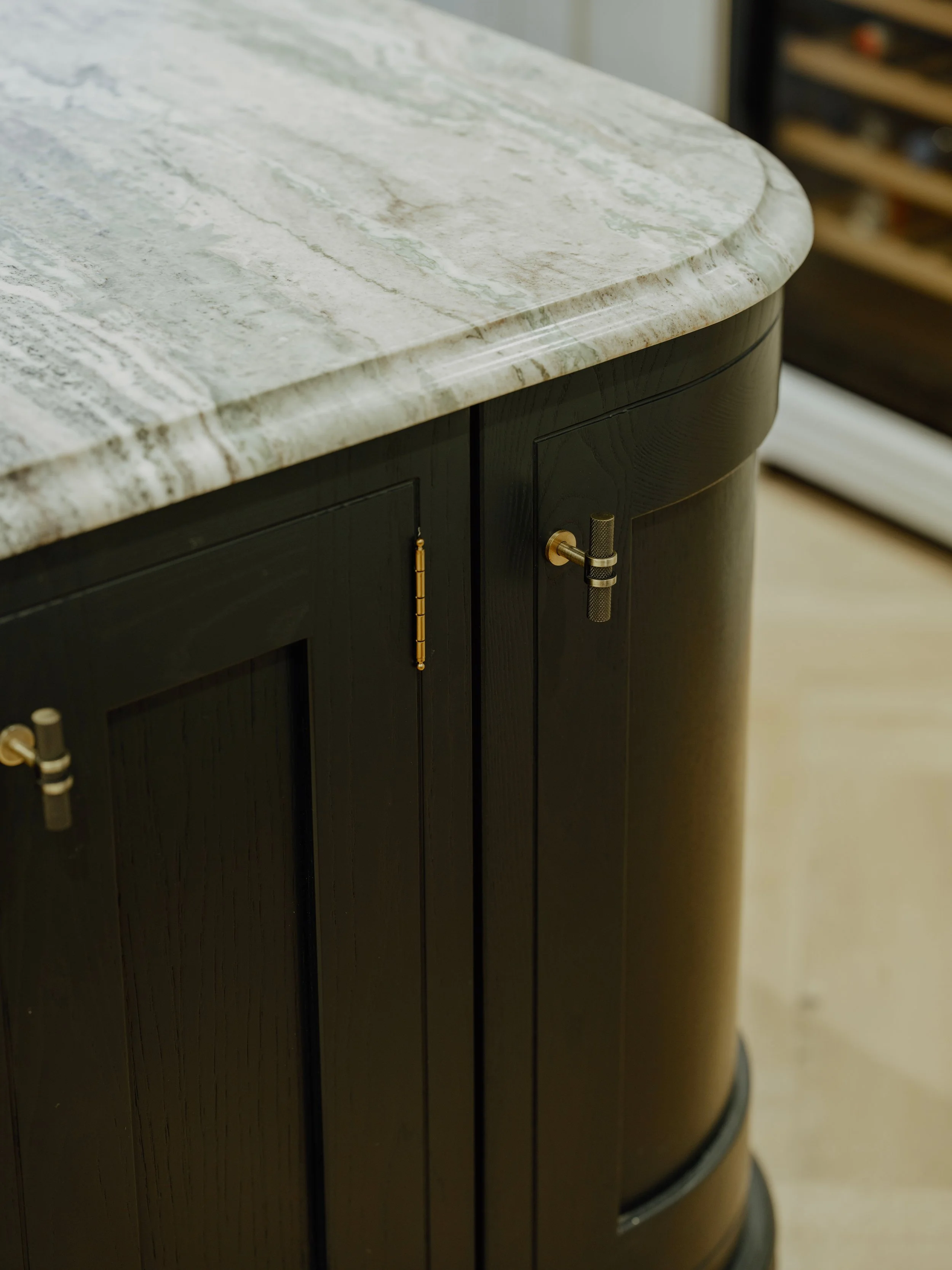 Curved black kitchen island with marble worktop and cabinetry at Project Orton.