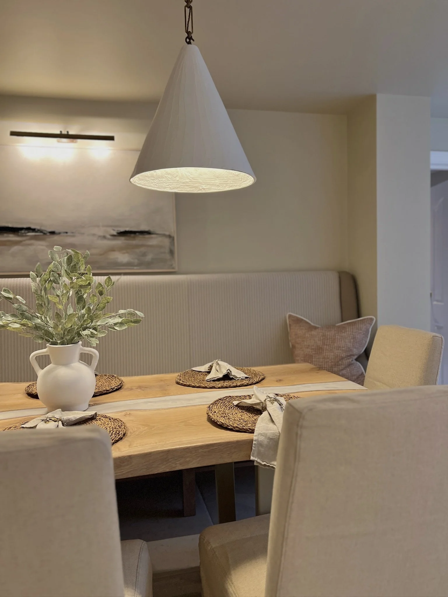 Custom scalloped banquette seating upholstered in neutral and stripe fabrics, creating a cosy dining nook with a bespoke river resin table.