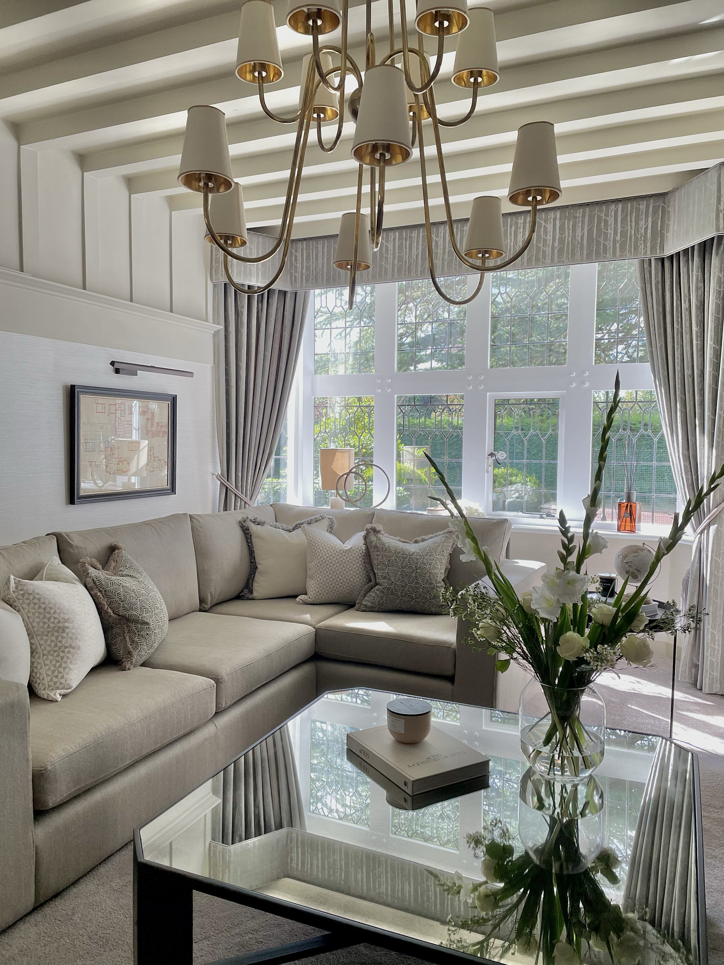 Elegant living room featuring a bespoke corner sofa, statement chandelier and original leaded windows within a Grade II listed West Midlands home.