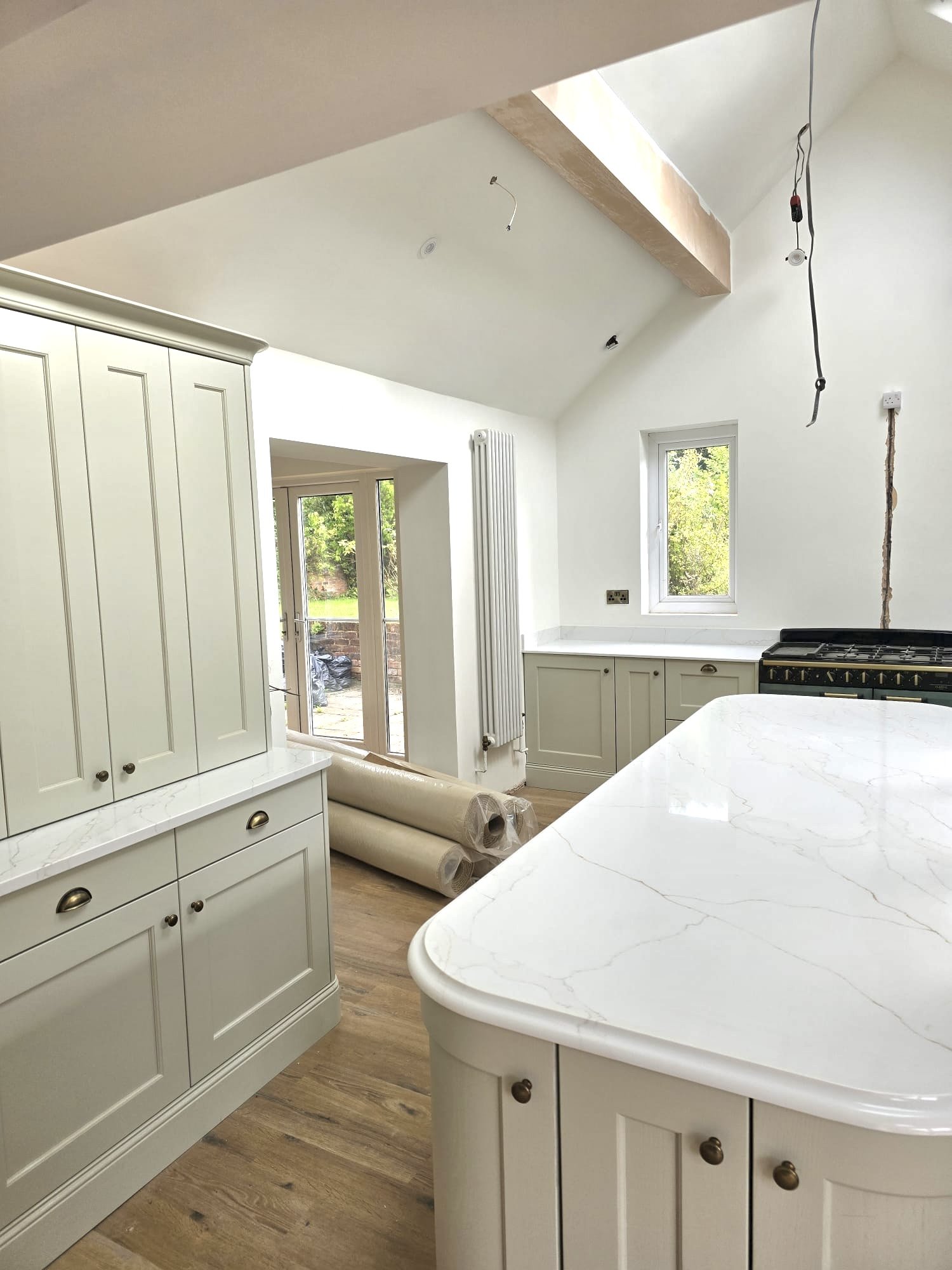 Family kitchen layout designed around a large central island, generous storage, natural light and a seamless connection to the garden.