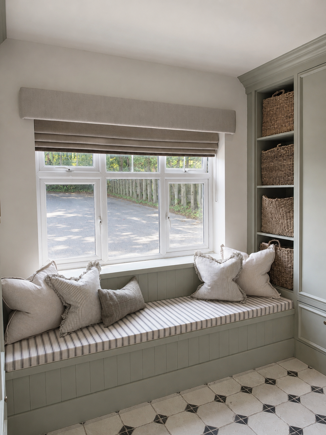 Bespoke window seat with integrated cabinetry and soft neutral cushions, creating a calming boot room within a thoughtfully designed family home.