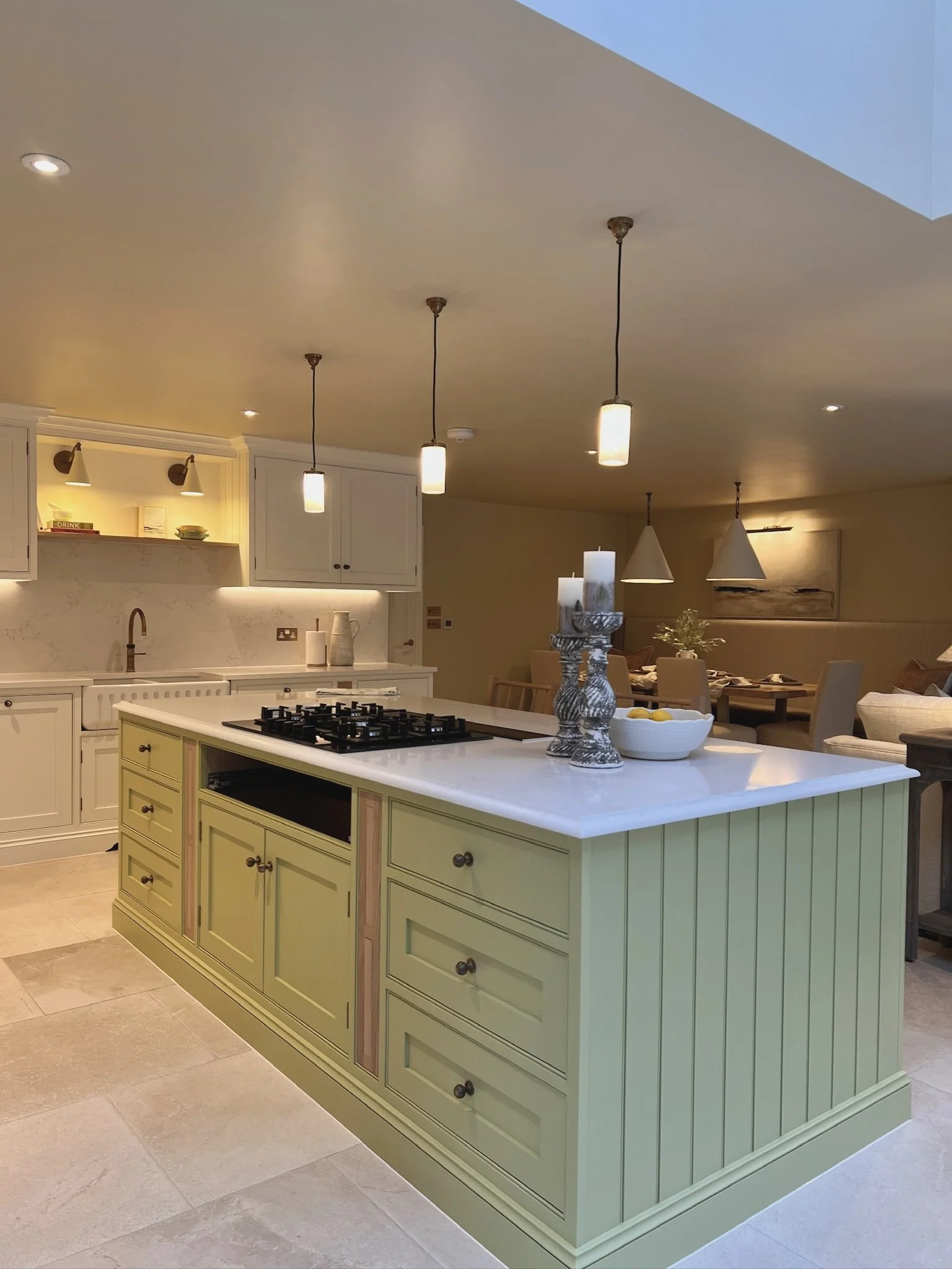 Contemporary country kitchen featuring a soft green island, shaker cabinetry and open plan living space inspired by relaxed Mediterranean interiors.